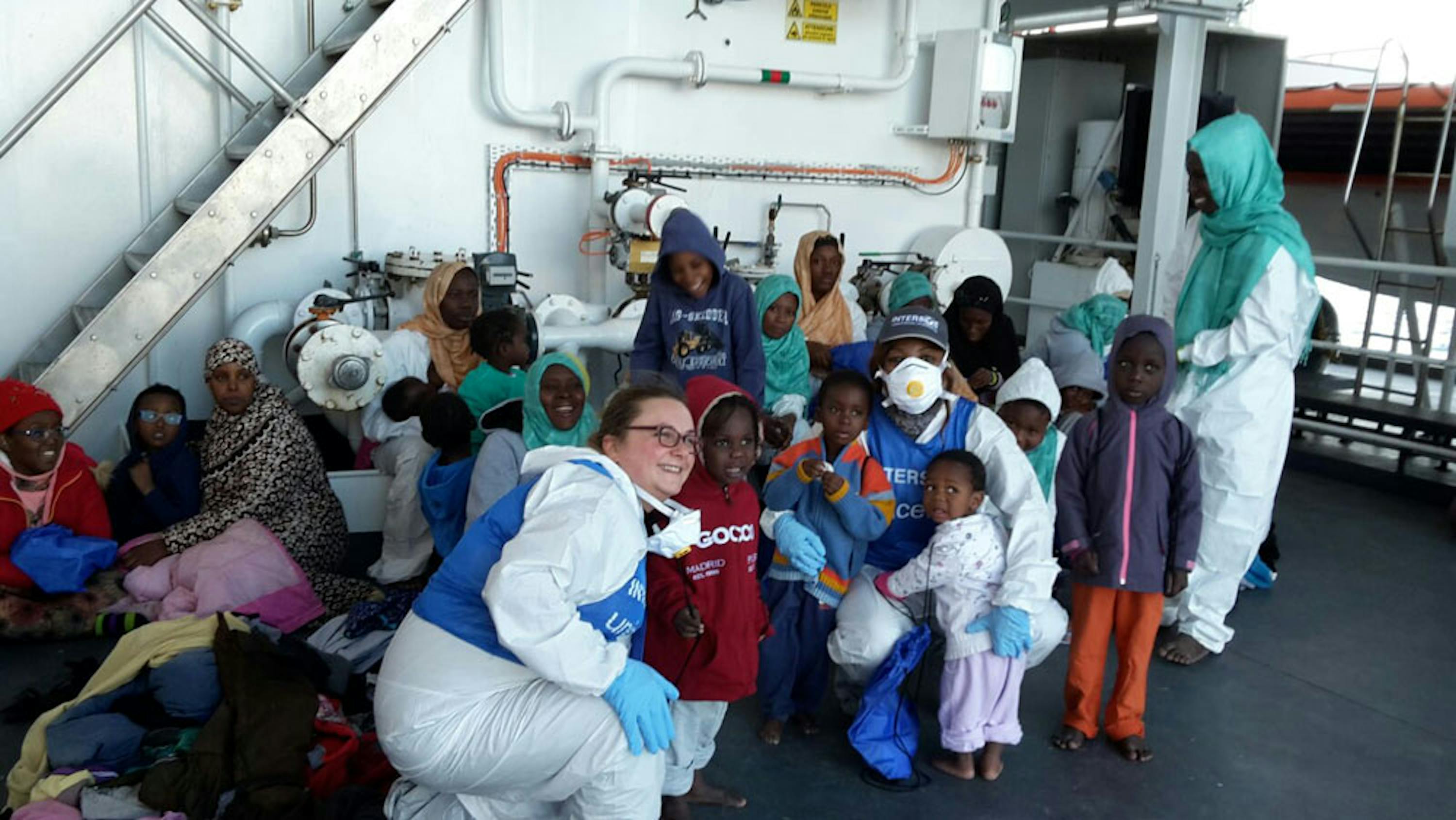 Bambini e mamme con due operatrici di INTERSOS-UNICEF su una nave della Guardia Costiera durante una recente missione di salvataggio nel Mediterraneo