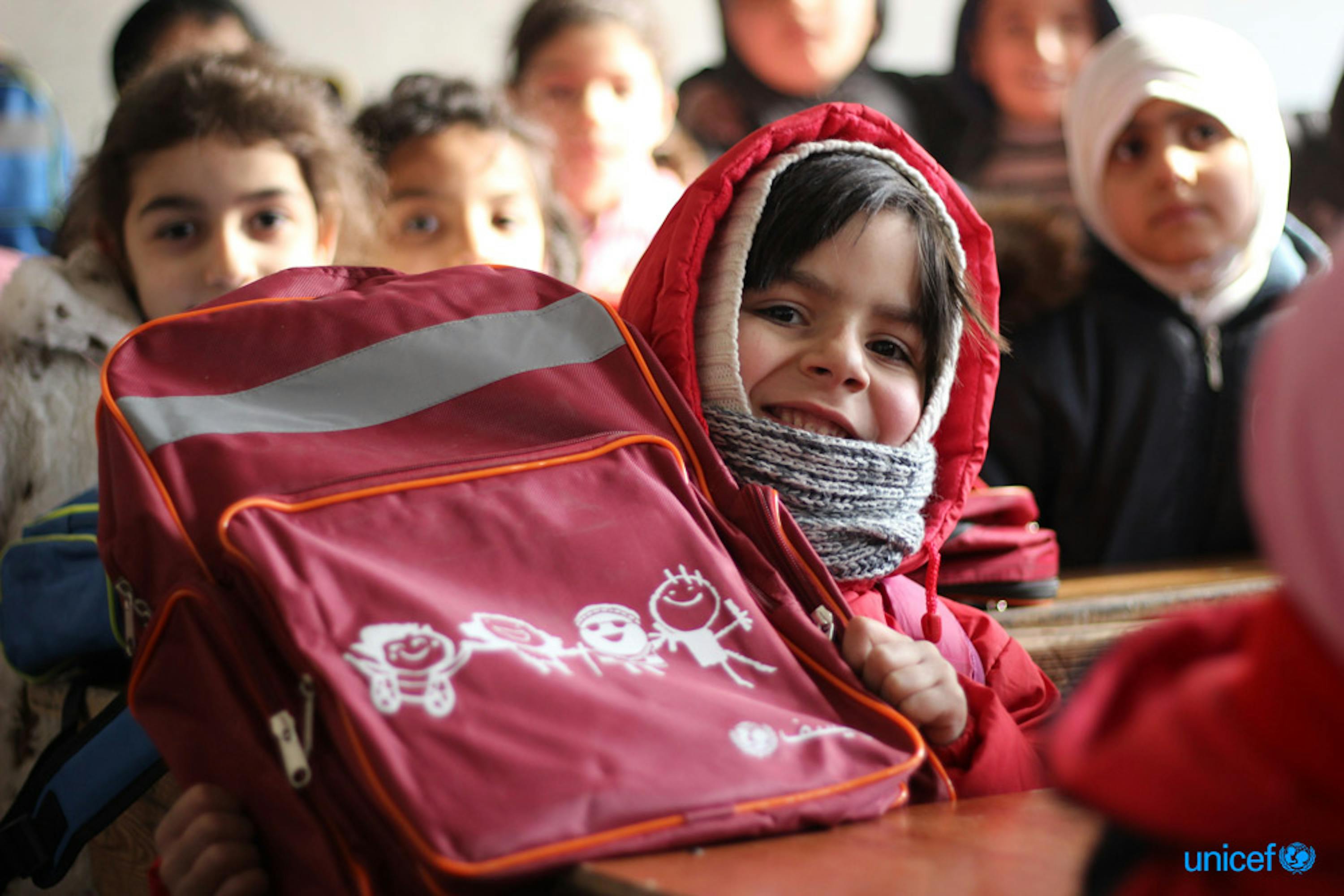 Una bambina sorride con lo zaino scolastico appena ricevuto dall'Unicef © UNICEF/UN051524/Al-Issa