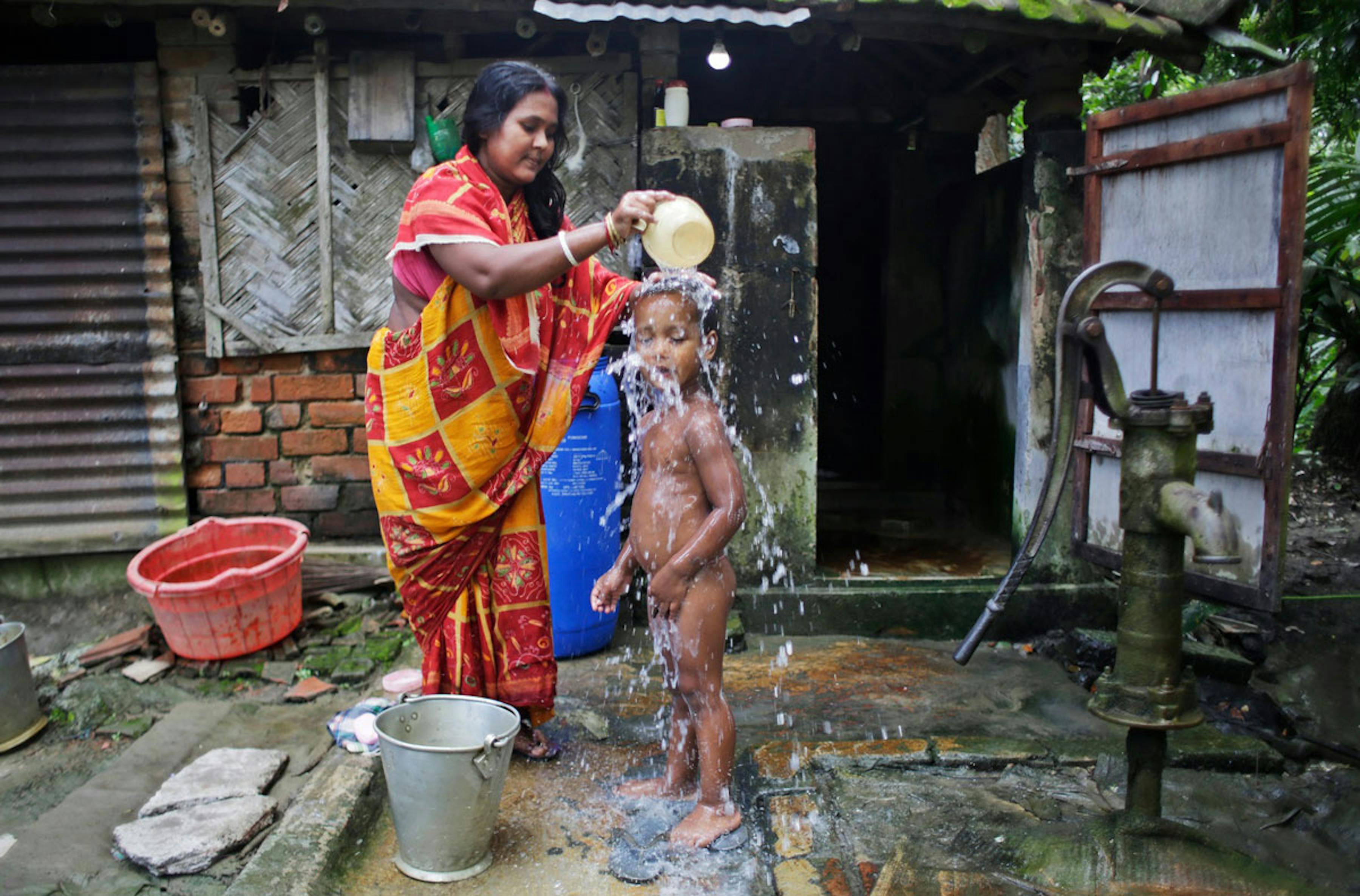 Una donna lava il suo bambino nel villaggio di Jawdanga, nello stato indiano del West Bengala. Due terzi della popolazione mondiale priva di acqua corrente vive in zone rurali - ©UNICEF/UN063155/Altaf Ahmad
