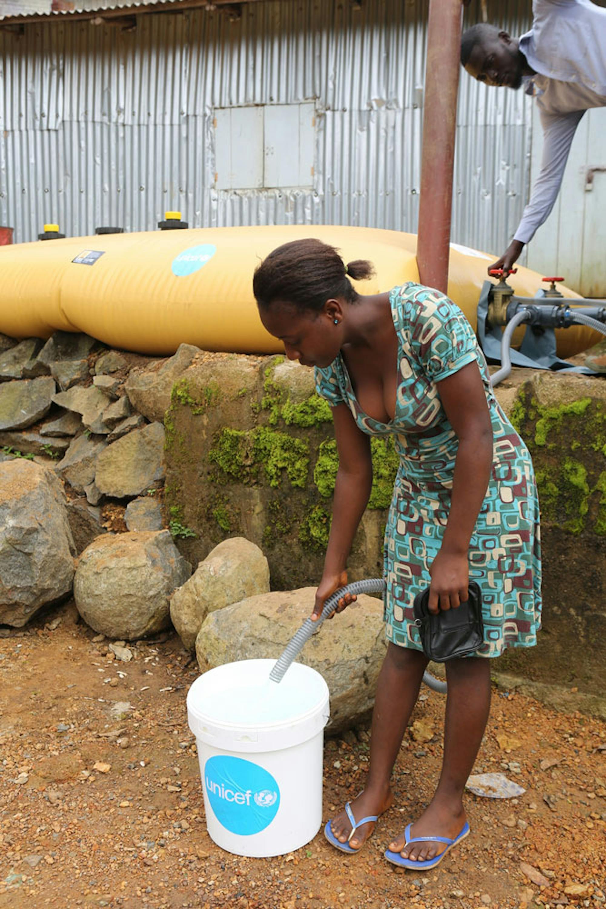 Una donna attinge acqua potabile da una cisterna installata dall'UNICEF a Regent, la cittadina della Sierra Leone maggiormente funestata dalle inondazioni dei giorni scorsi - ©UNICEF/UN076070/James