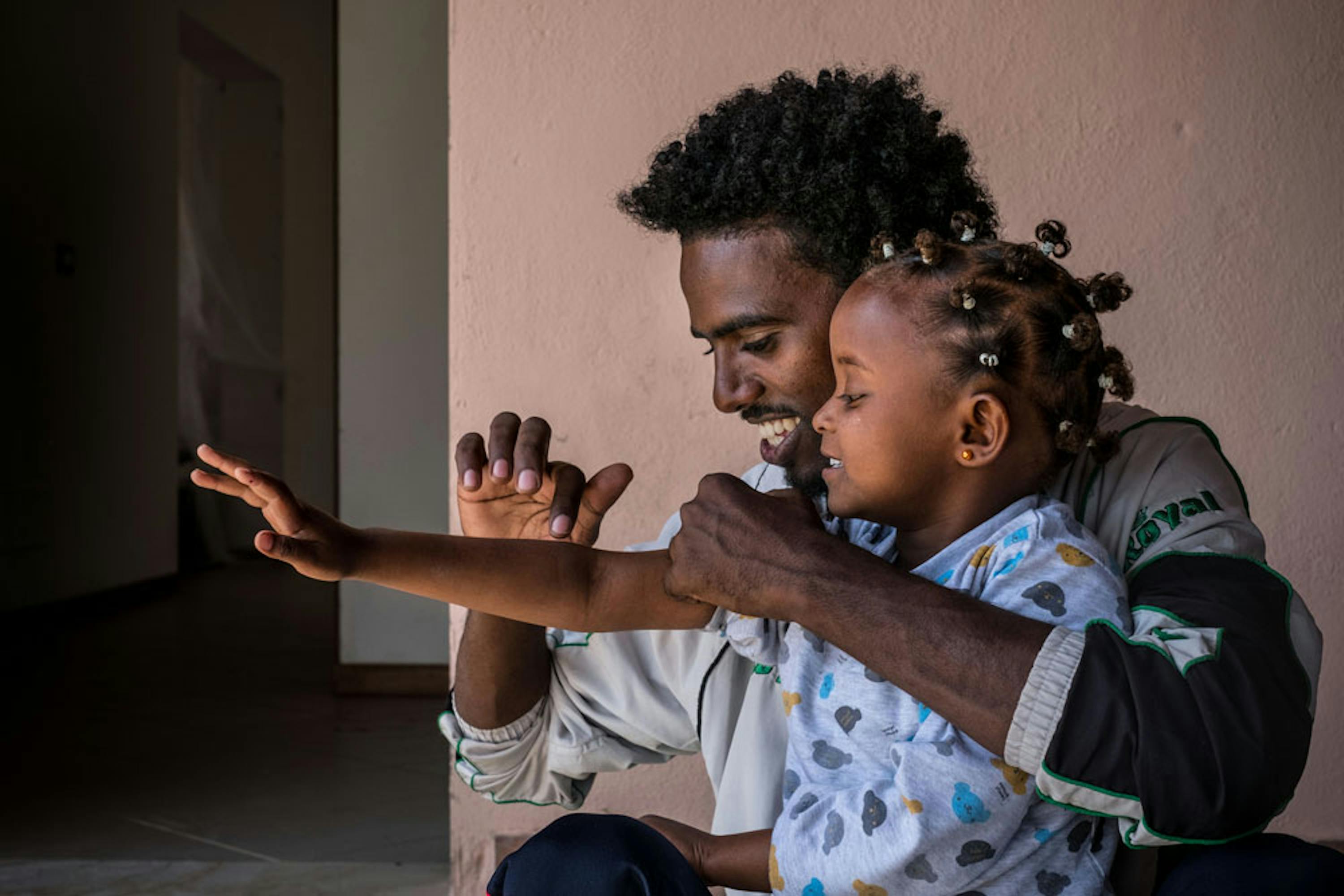 Tesfit, 25 anni, gioca con Bettie, 3 anni, figlia di un suo amico, nel Centro per richiedenti asilo di Mineo (CT). Entrambi provengono dall'Eritrea - ©UNICEF/UN020042/Gilbertson VII Photo