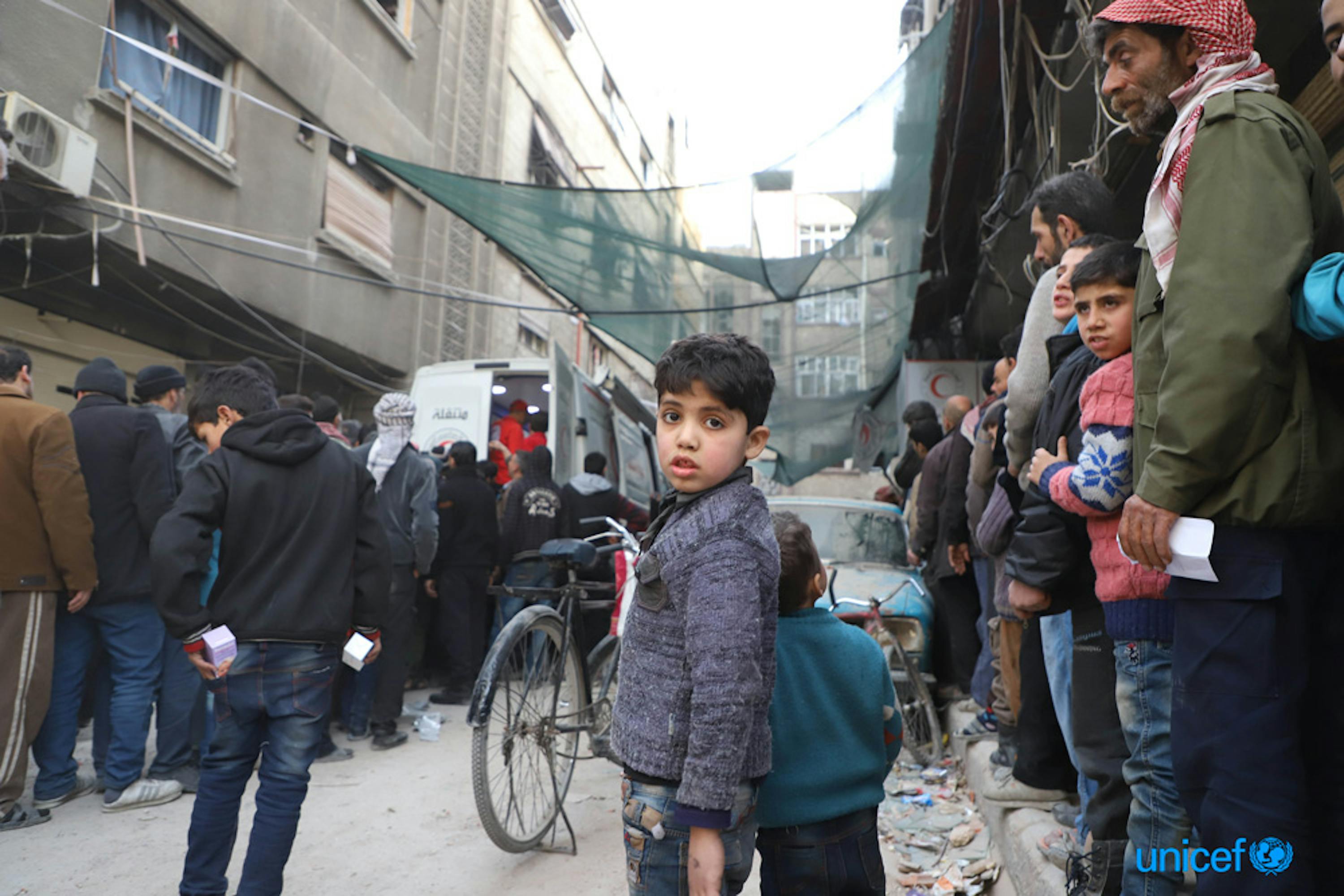 Gli abitanti di Duma, tra cui i bambini, fanno la fila  a un convoglio congiunto UNICEF, ONU e Mezzaluna Rossa siriana di 46 camion, che ha portato aiuti umanitari per 27.500 persone nel  Ghouta orientale, Siria -  © UNICEF/UN0162765/Al-Mohibany