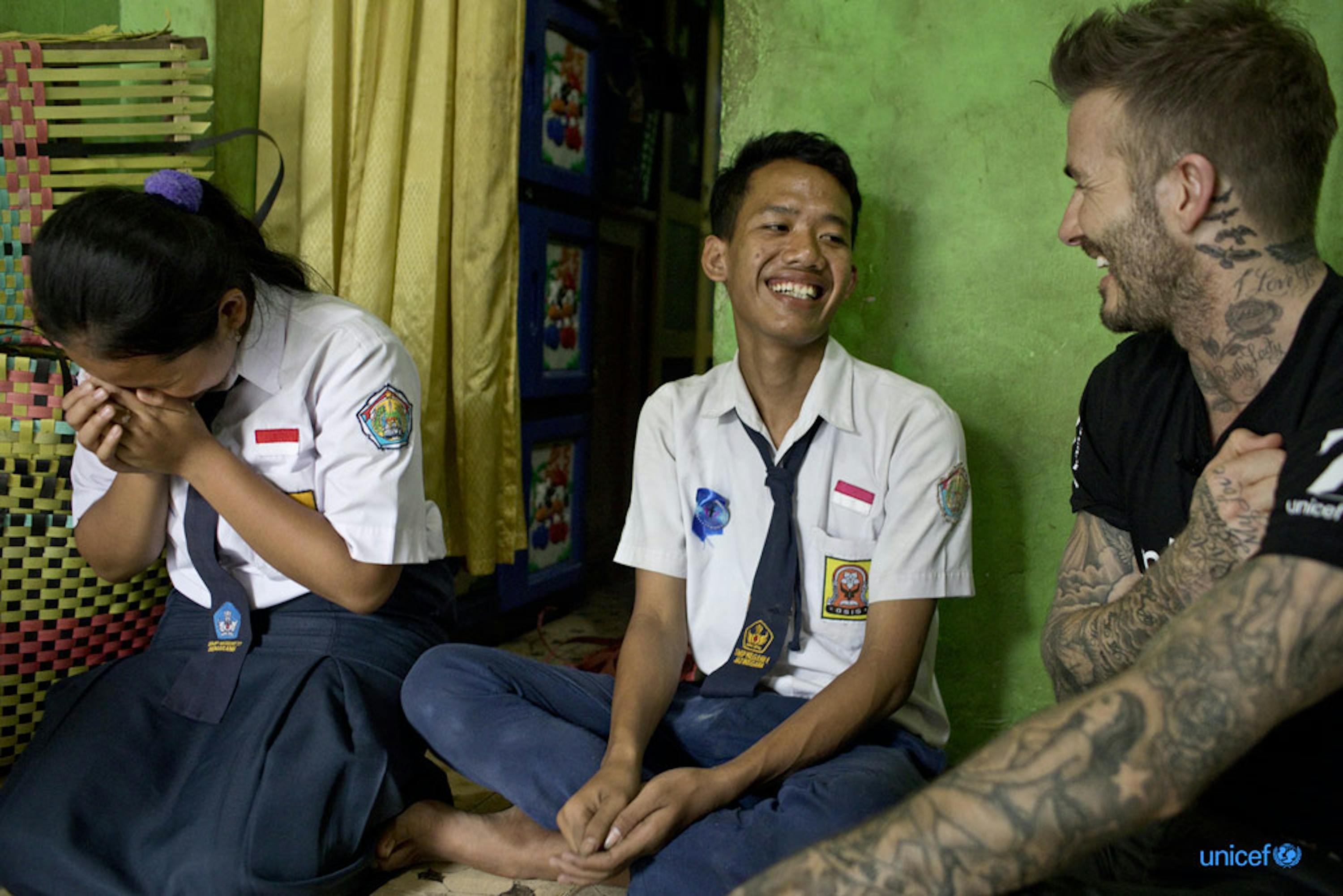 David Beckham sorride con Sripun, 15 (a sinistra) e il suo amico Ego (al centro) nella casa di sua nonna a Semarang, in Indonesia - © UNICEF/UN0188664/Modola