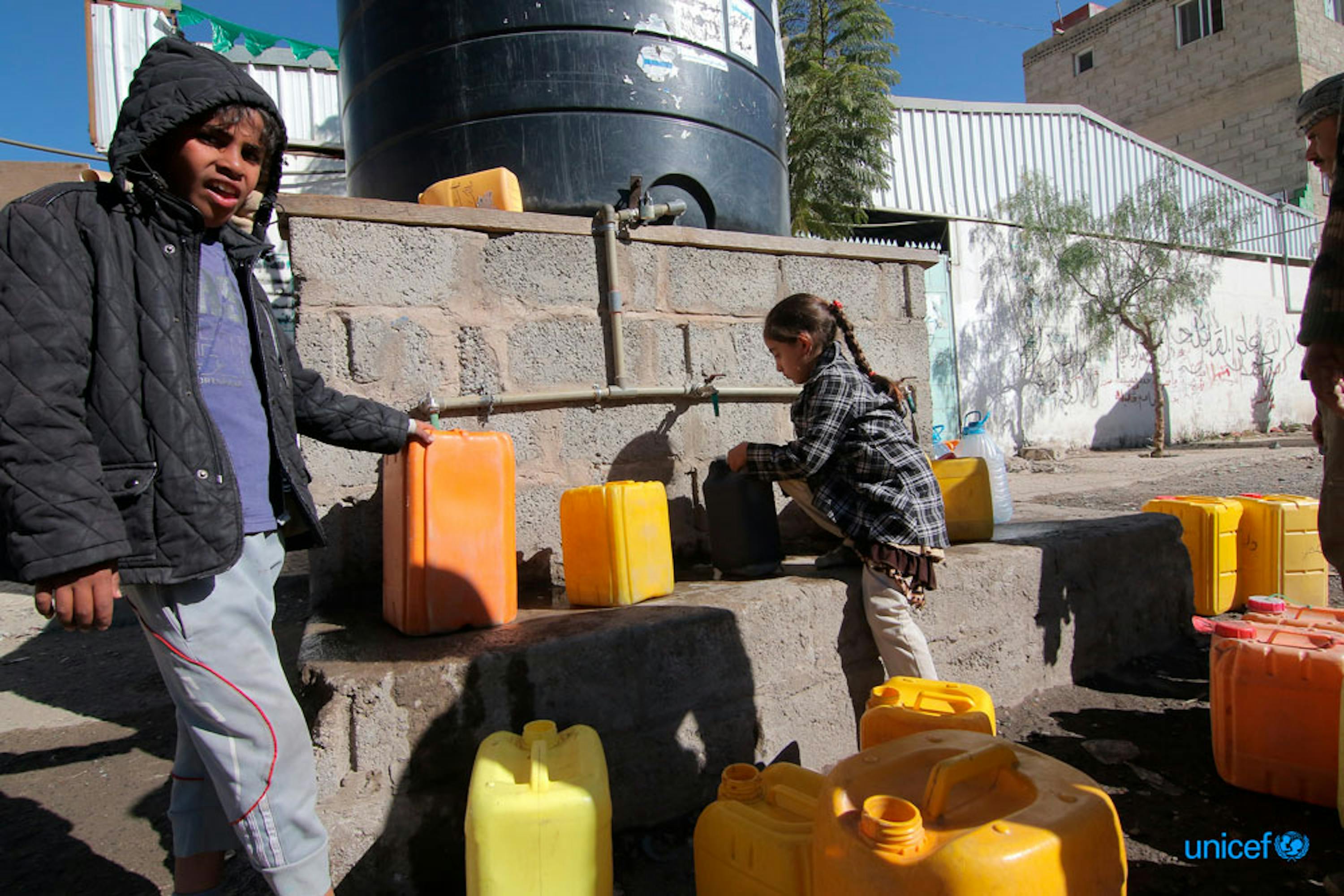 Alcuni bambini riempiono i contenitori di acqua potabile da un serbatoio in una strada di Sana'a,  Yemen  © UNICEF/UN0153966/Alawami