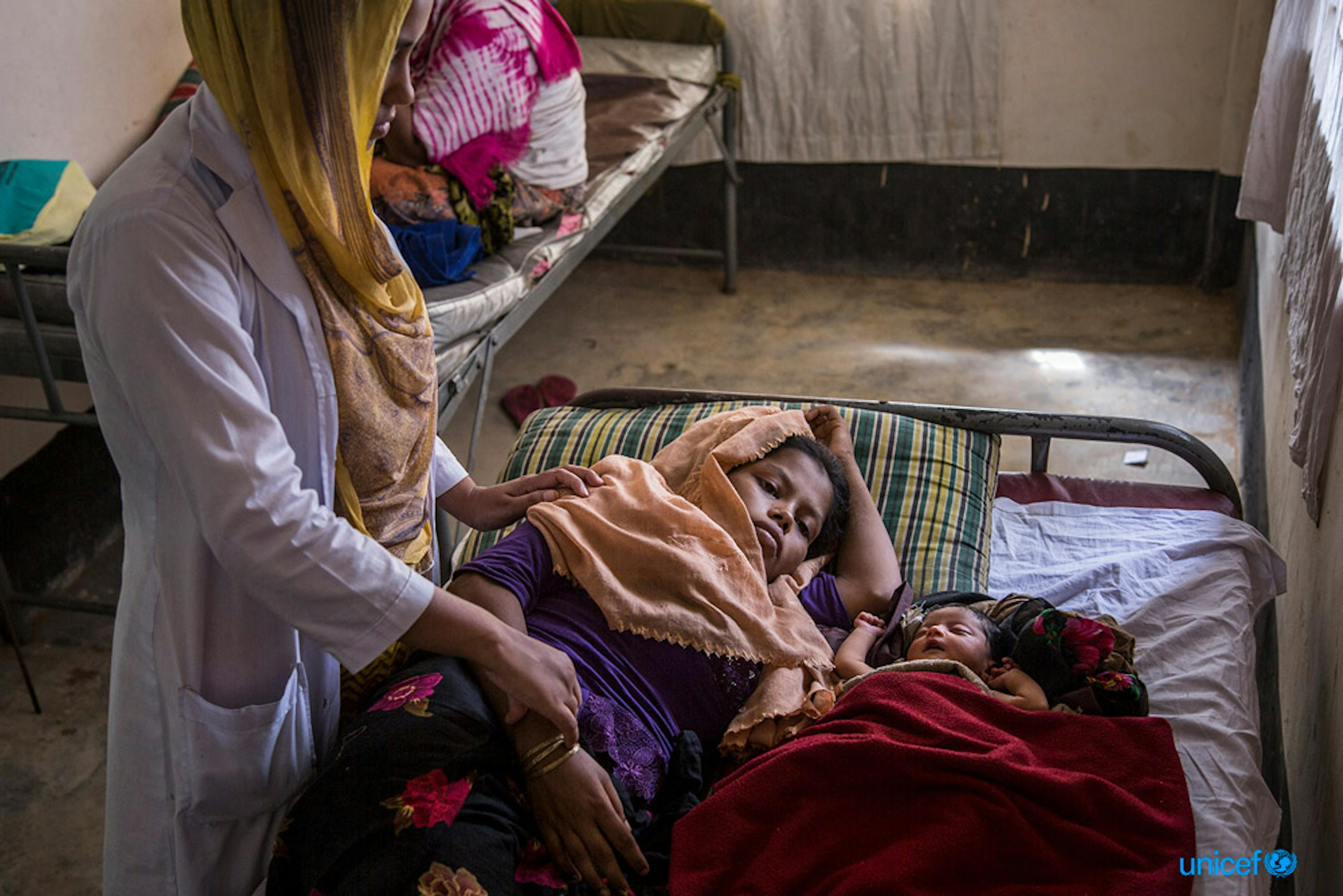 Un'ostetrica con una donna e la sua bambina, nata da soli 3 giorni. nell'ambulatorio del campo di Kutupalong a Cox's Bazar (Bangladesh) - ©UNICEF/UN0139593/LeMoyne