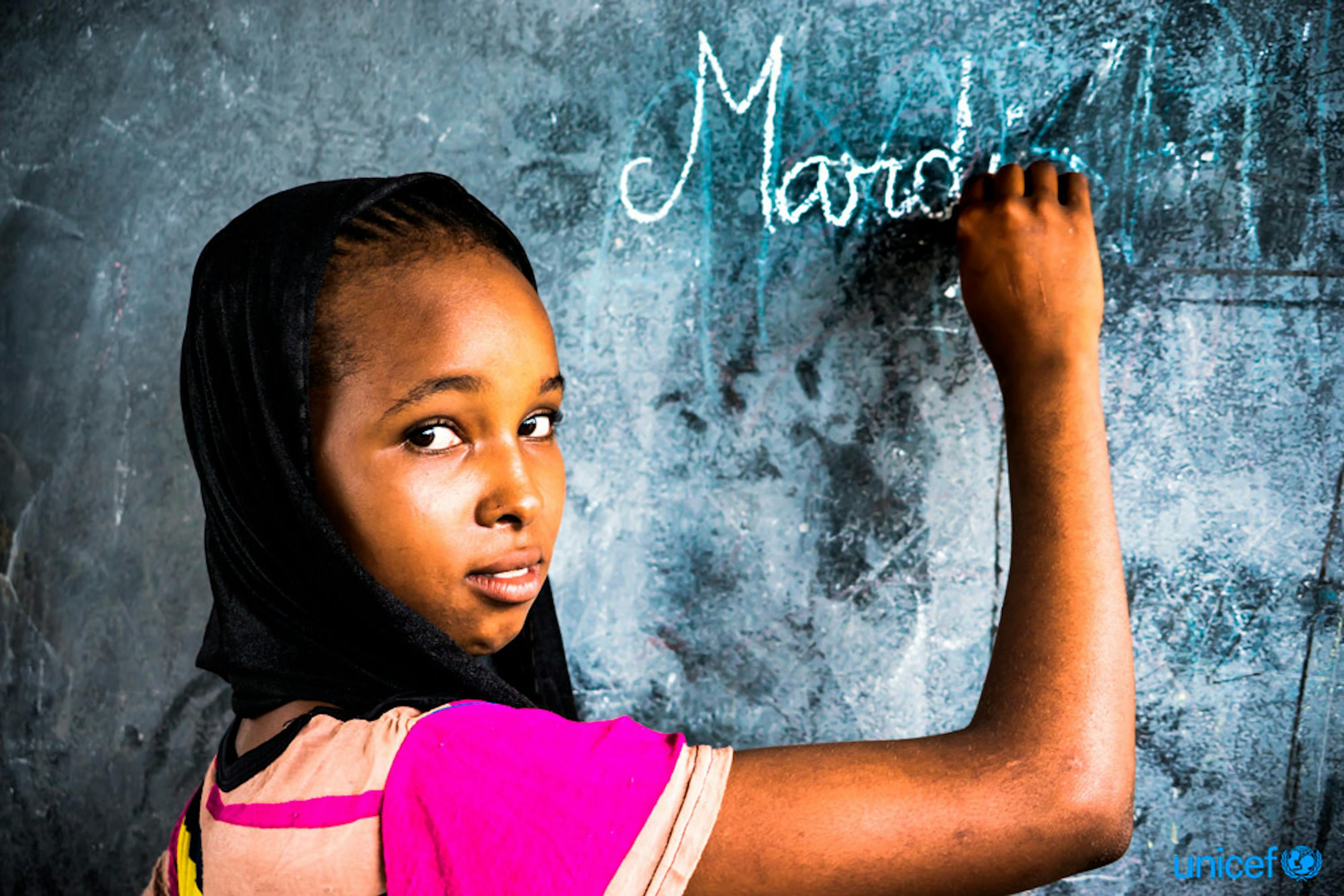 Hawa Oimar, 15 anni, scrive su una lavagna in una classe della sua scuola a Danamadja, Ciad . l'UNICEF fornisce un kit per donne e ragazze, che includono assorbenti igienici,  torcia elettrica e fischietto © UNICEF/UN0122322/Faffin