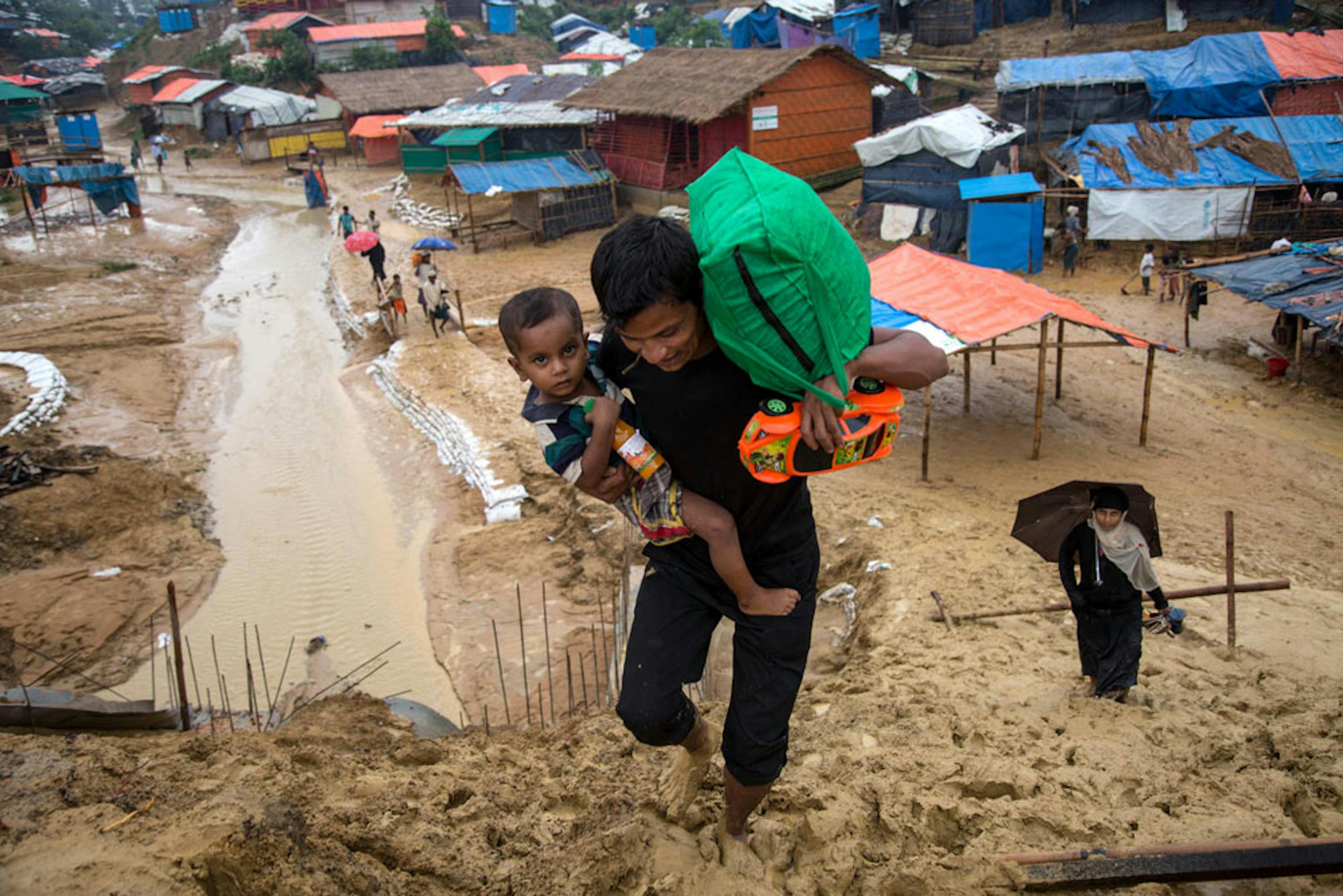 Padre e figlio arrancano nel fango dell'immenso campo profughi di Kutupalong (Bangladesh), il più grande al mondo. Sono circa 900.000 i rifugiati Rohingya attualmente in Bangladesh - ©UNICEF/UN0216991/LeMoyne
