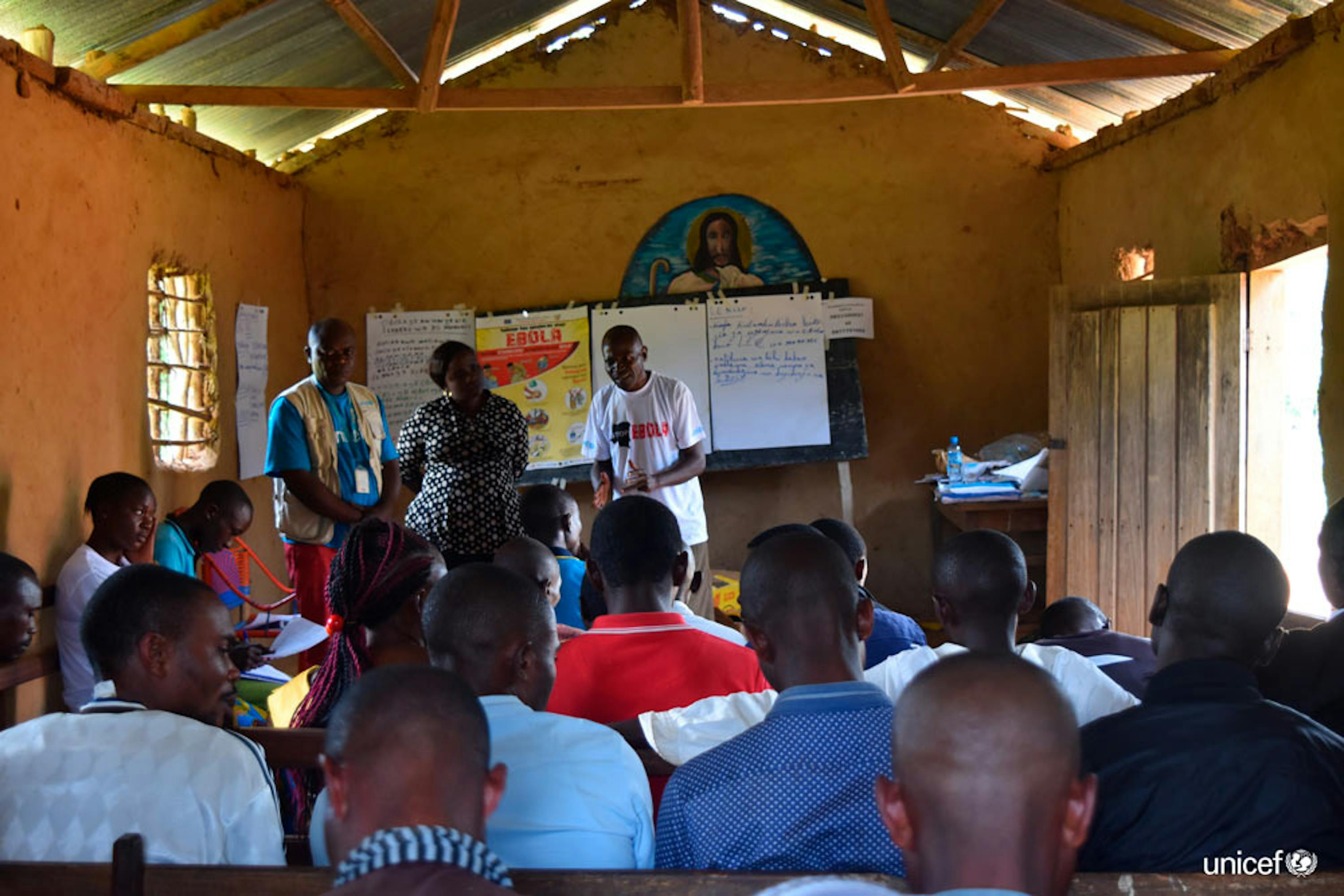 Congo, un sopravvissuto all'Ebola e un operatore dell'Unicef esortano i membri di una comunità locale nel Nord Kivu a condividere le informazioni sui sintomi dell'epidemia - © UNICEF/UN0231606/Herrmann