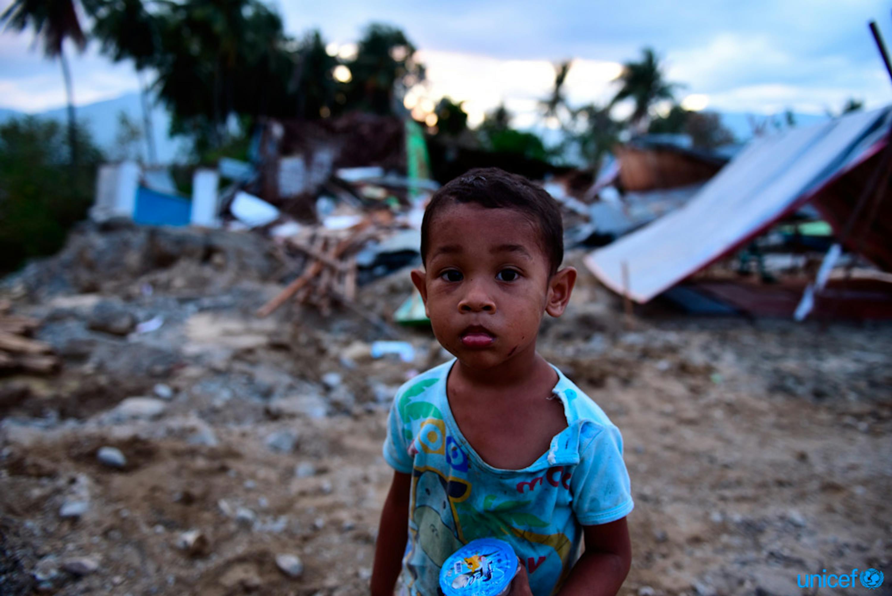 Muhamad Nafi, di 2 anni, è tra le rovine della sua casa distrutta dal recente tsunami nel villaggio di Lolu,  a Palu, nelle Sulawesi centrale - © UNICEF/UN0245434/Wilander