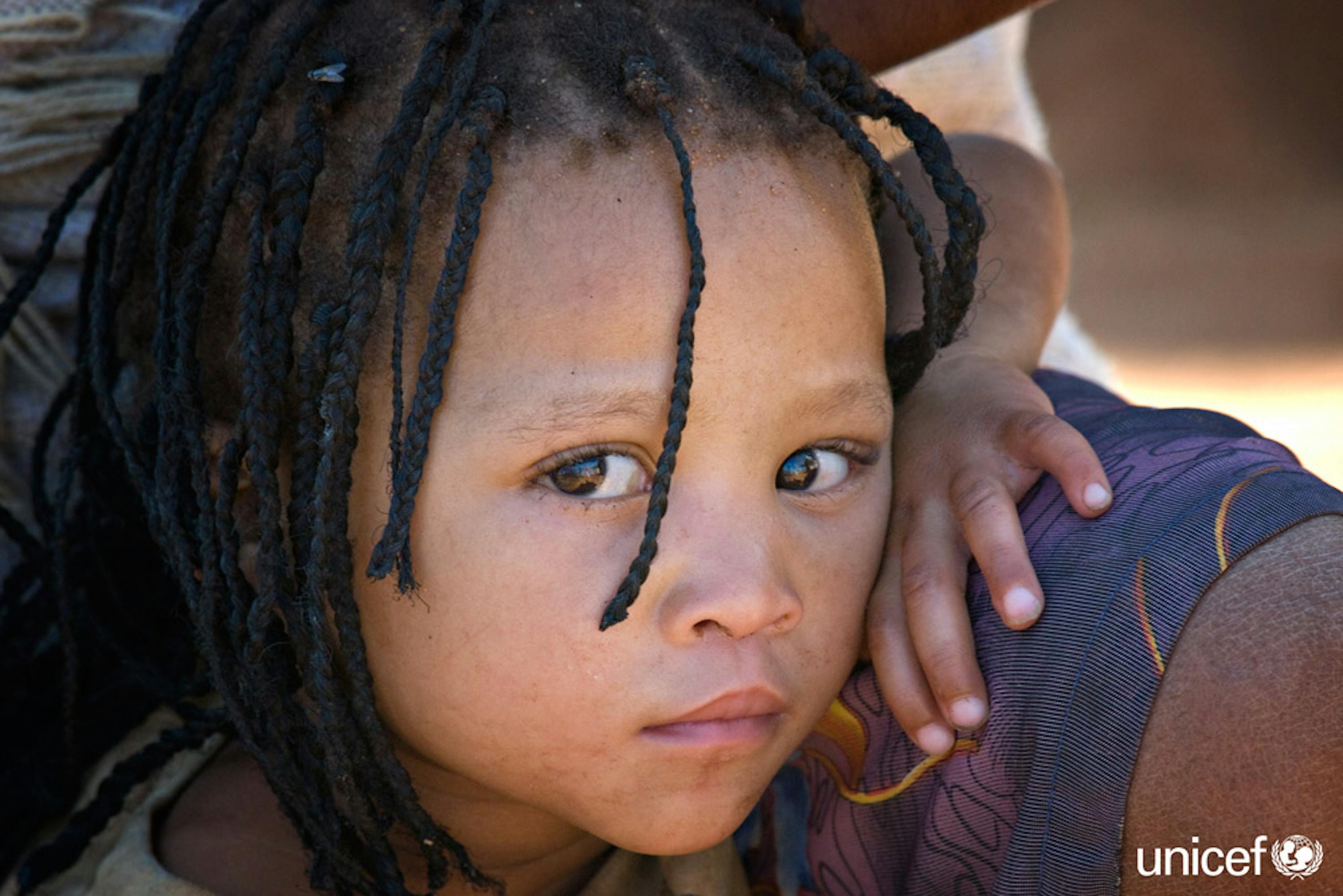 Namibia - Una bambina indigena del gruppo etnico San siede con sua madre fuori dalla loro casa nell'insediamento di  Epako, un sobborgo della città di Gobabis nella regione di Omaheke, vicino al confine con il Botswana - © UNICEF/UNI99397/Isaac