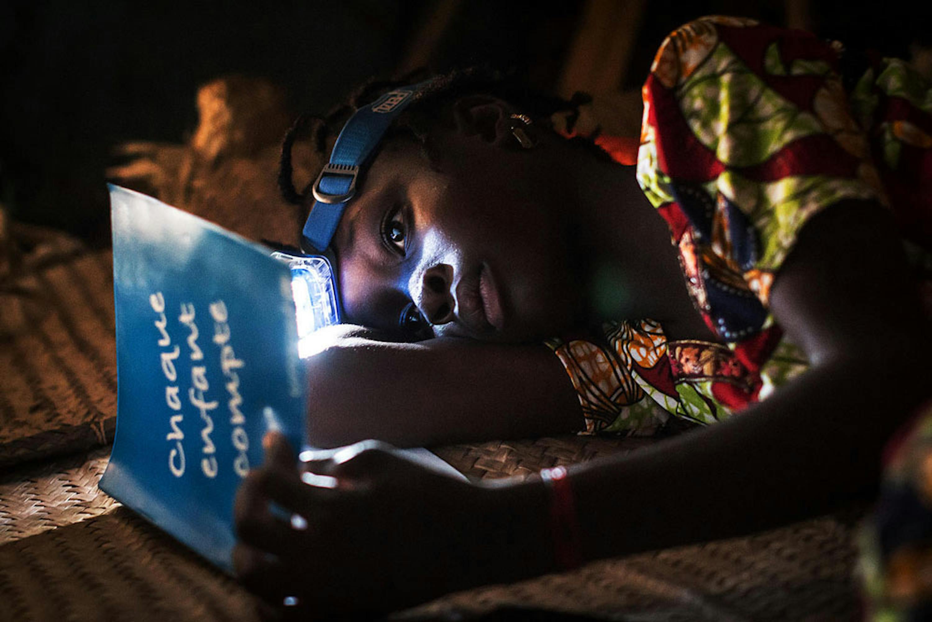 In un villaggio del Mali Koumberé, 12 anni, ripassa la sua lezione prima di addormentarsi. Koumberé è uno dei tanti bambini che l'UNICEF aiuta a proseguire gli studi dopo che la sua scuola è stata chiusa a causa del conflitto - ©UNICEF/UN0238530