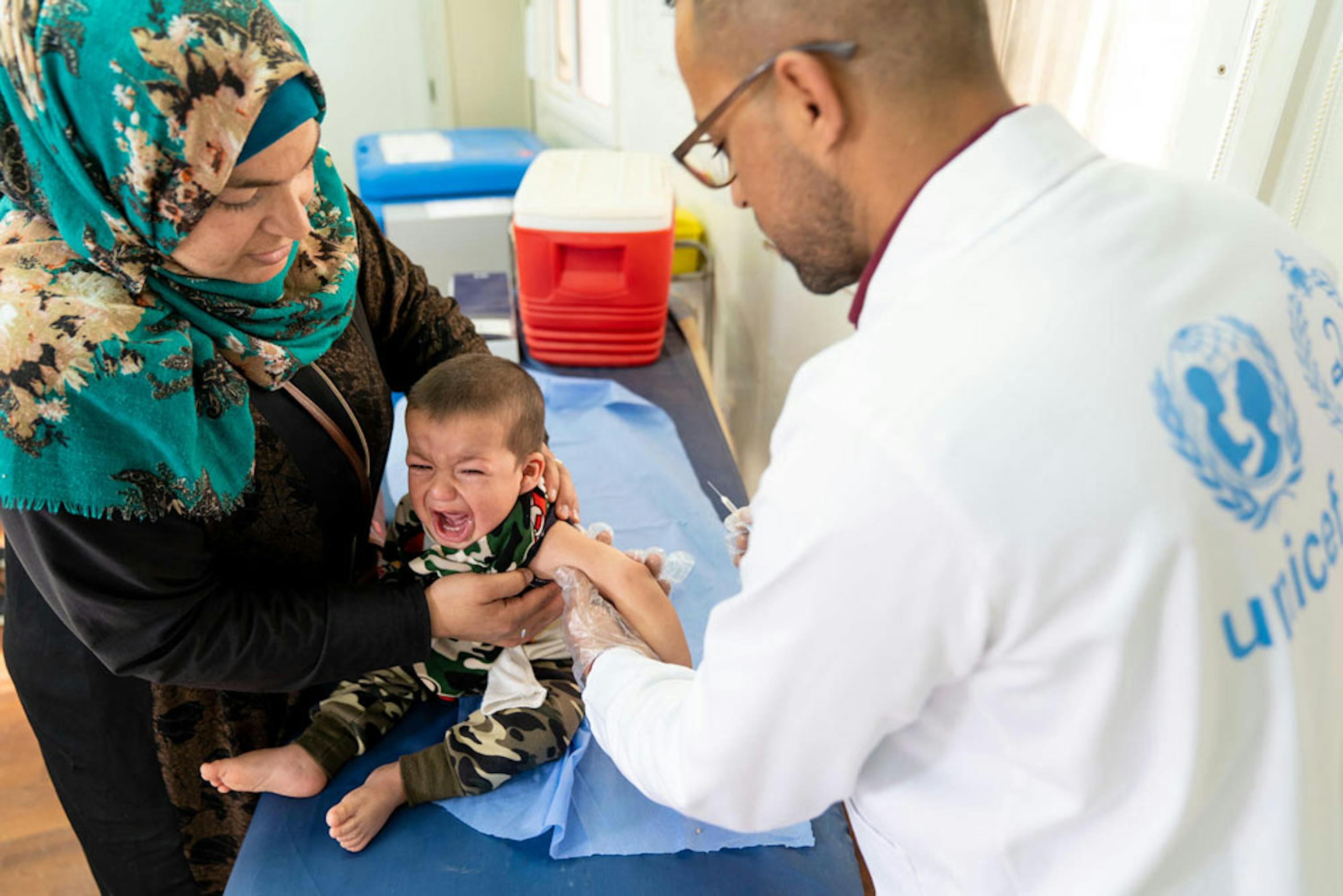 Ahmad, 1 anno, riceve una dose di vaccino trivalente MMR contro morbillo, parotite e rosolia) nell'ambulatorio del campo profughi di Azraq (Giordania). Ahmad e la sua famiglia sono originari di Aleppo (Siria) - ©UNICEF/UN0303616/Herwig