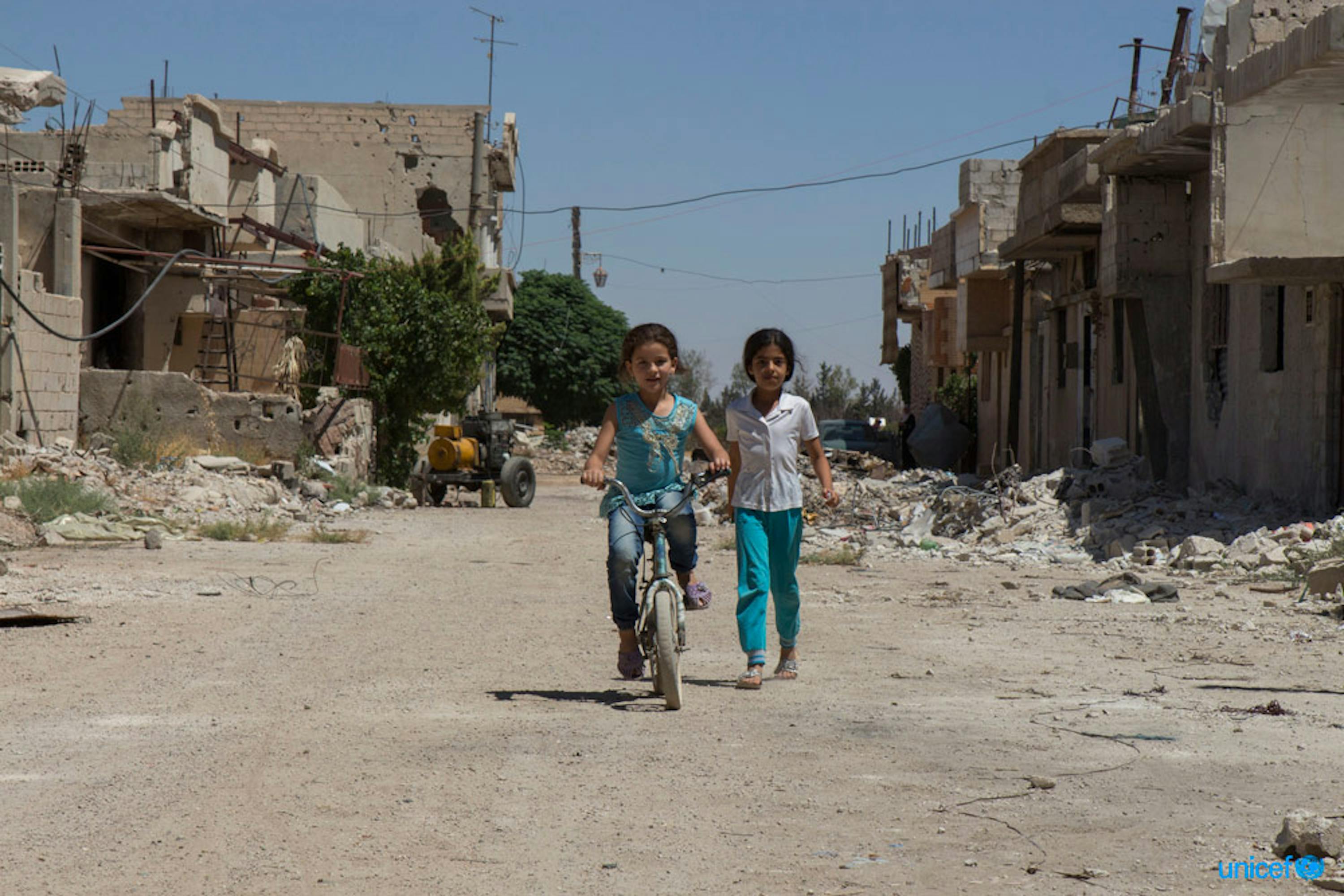 Siria - Sham, una bambina di 10 anni è in sella alla sua bicicletta di fronte a quella che era la sua casa. © UNICEF/UN073942/Nader