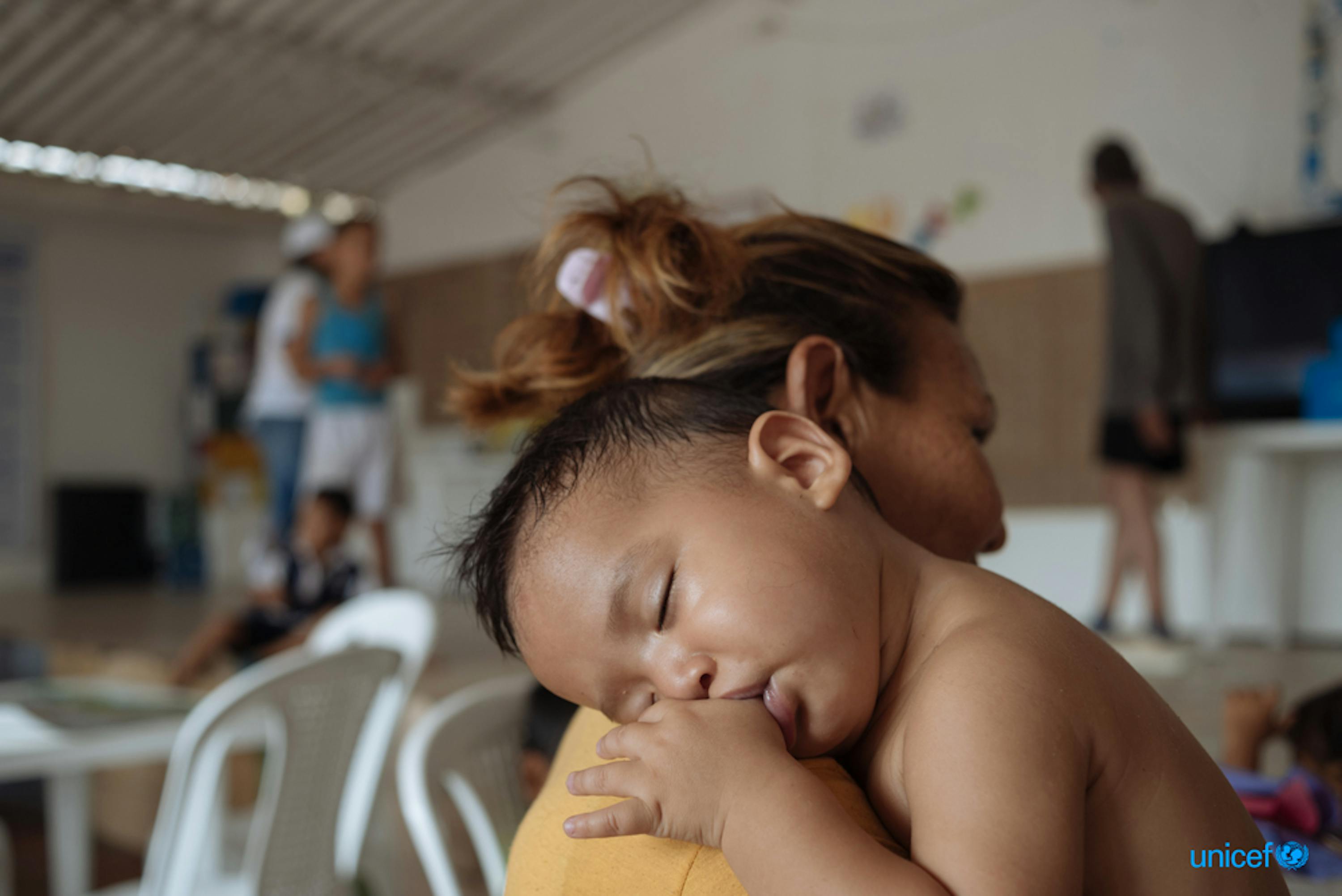 In Colombia, un bambino riposa sulla spalla di sua madre presso il Friendly Space (CATM) a Cucuta, dove l'UNICEF fornisce attività di apprendimento per i bambini migranti e i genitori del Venezuela. © UNICEF/UN0304586/Arcos