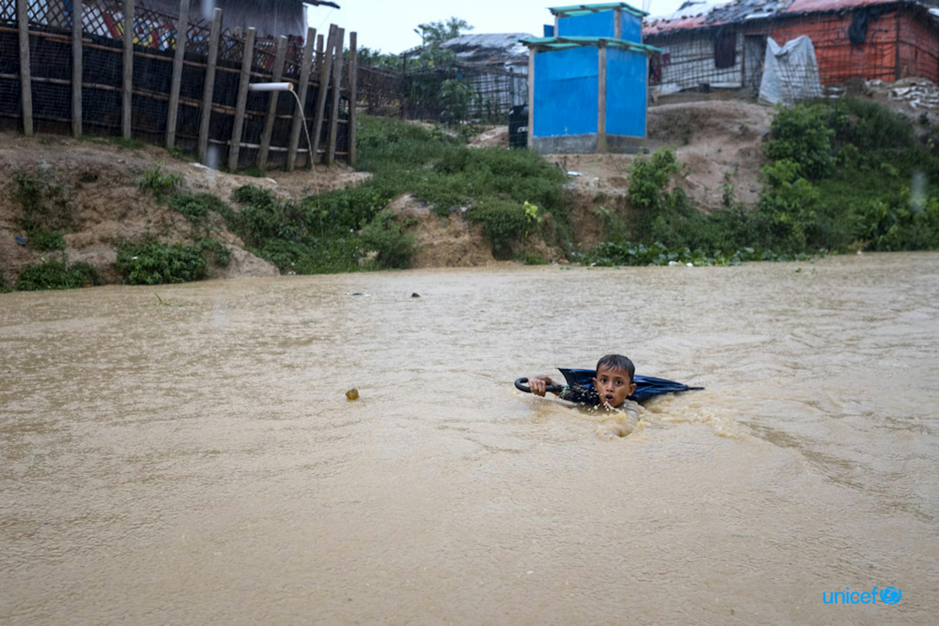 Bangladesh, un giovane ragazzo naviga in un fiume gonfio dai giorni di pioggia dei monsoni - © UNICEF/UN0326875/Nybo