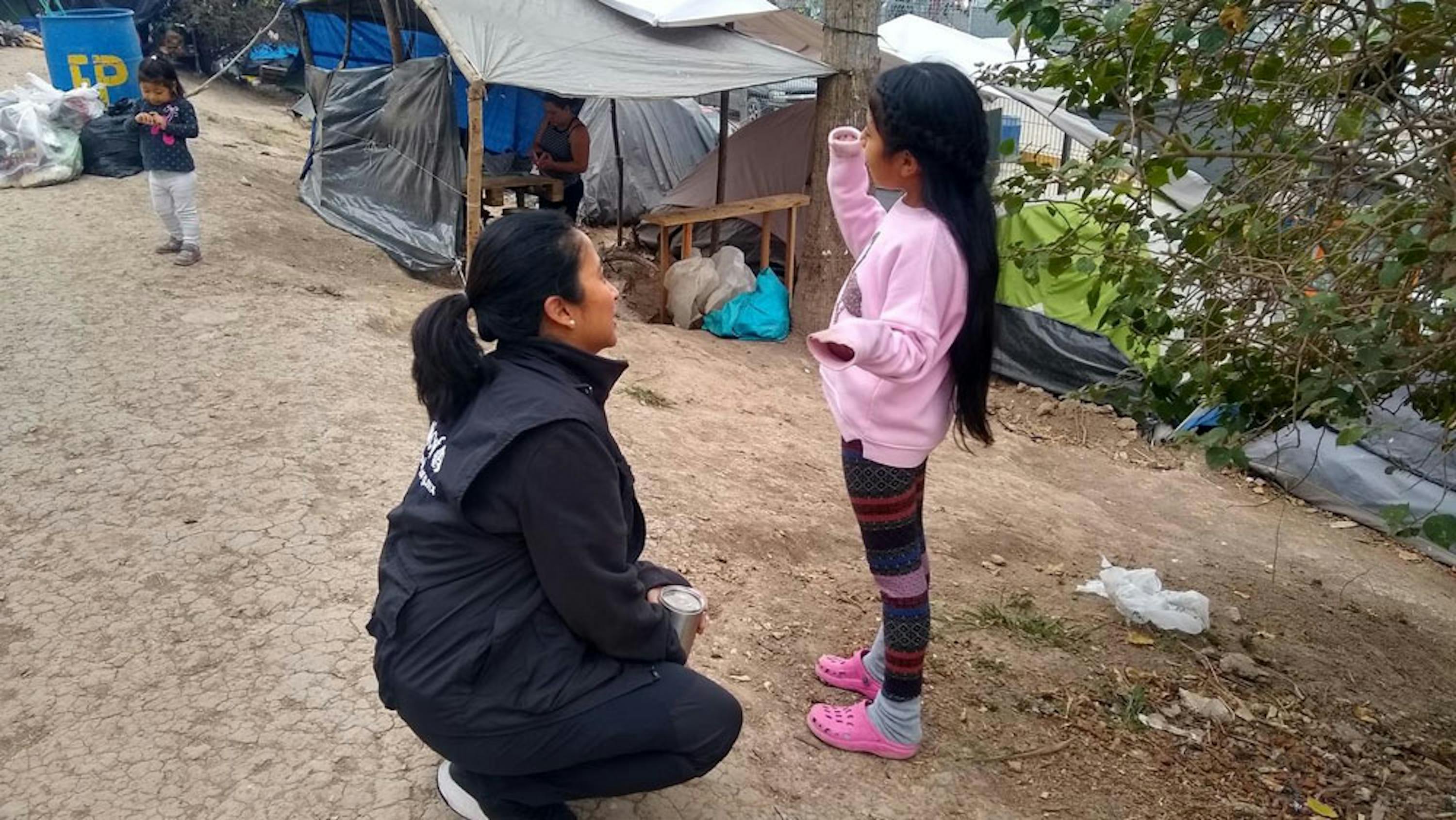 La vicerappresentante dell'UNICEF in Messico Pressia Arifin-Cabo parla con una bambina nell'accampamento di Matamoros, al confine tra Messico e USA - © UNICEF/UNI285132_Vergara Toache
