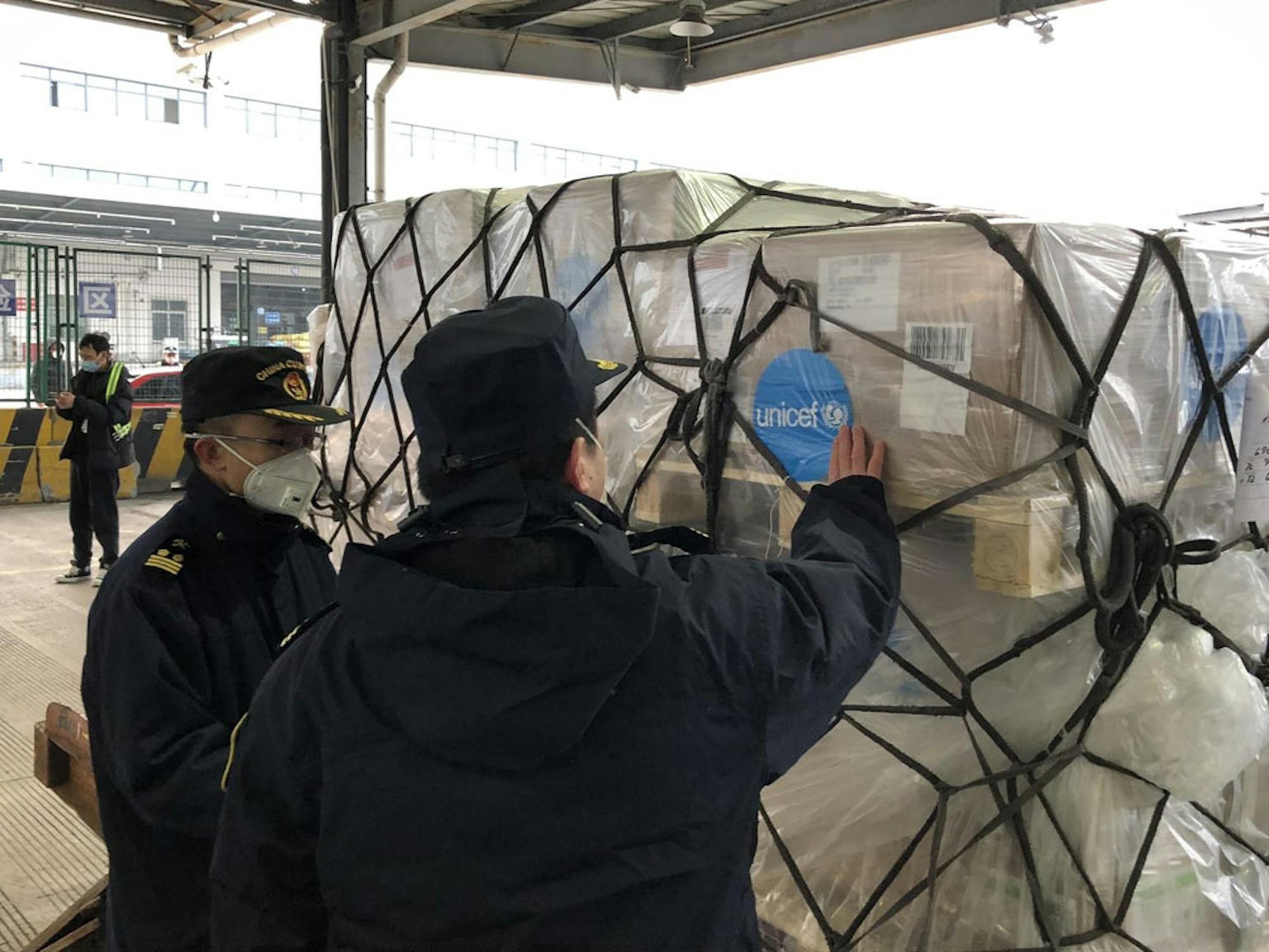 Addetti dell'aeroporto internazionale di Shangai (Cina) ispezionano il carico giunto dalla UNICEF Supply Division di Copenaghen con migliaia di tute protettive, mascherine e altri articoli per il contrasto dell'epidemia di SARS-CoV-2 - © UNICEF/UNI284471