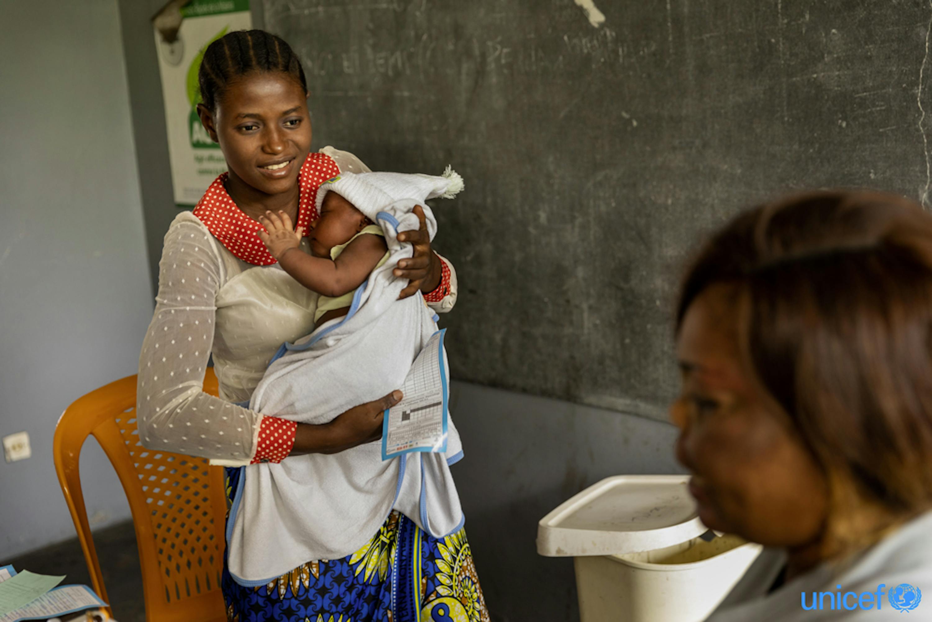 Una mamma col suo bambino di 1 mese in attesa di ricevere il vaccino contro il morbillo a Nsele, nella Repubblica Democratica del Congo - © UNICEF/UNI308216/Brown