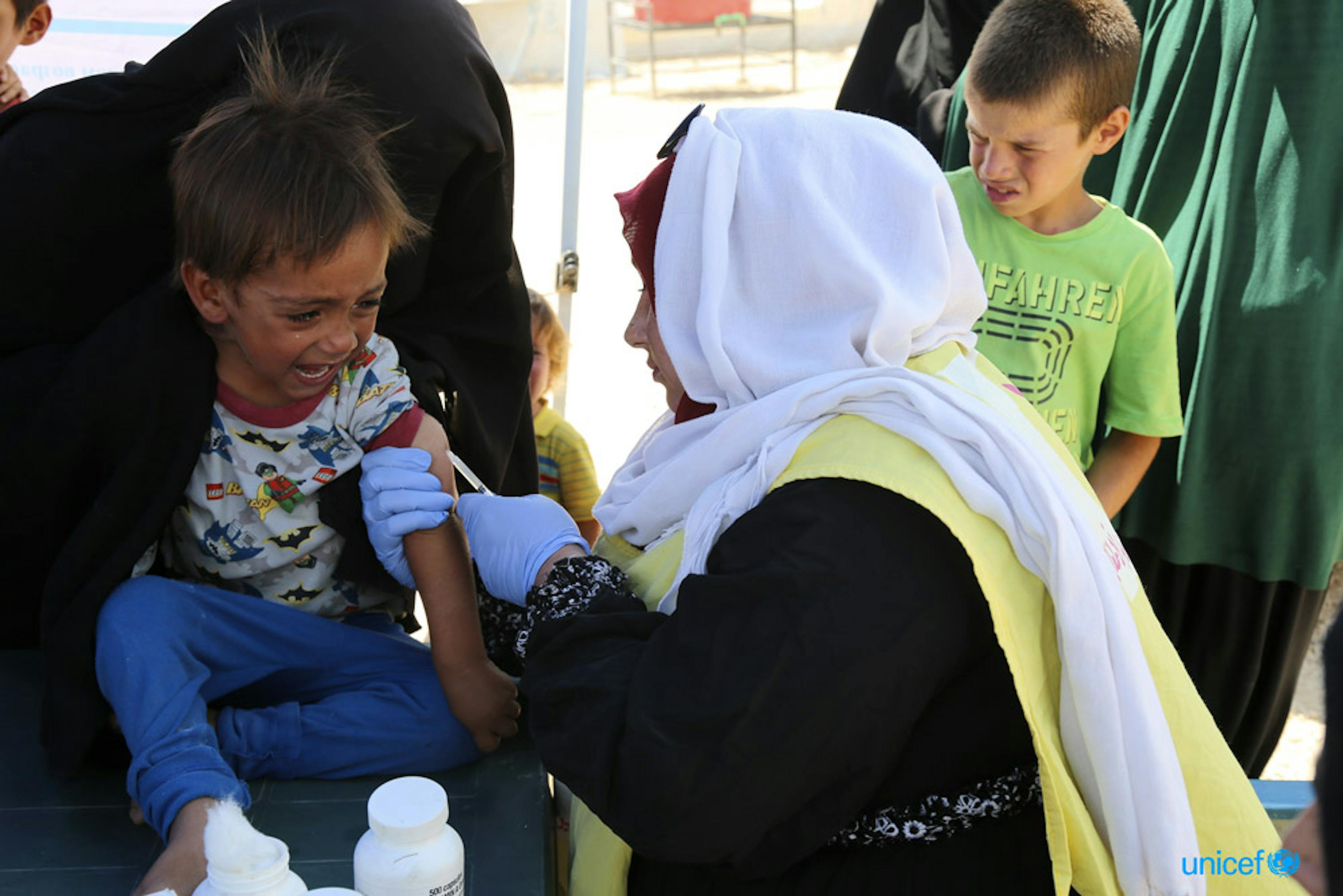 Un'operatrice di un team sanitario mobile dell'UNICEF somministra una vaccinazione a una bambina nel campo di Al-Hol, nel nord-est della Siria - ©UNICEF/UN0327927/Hawas