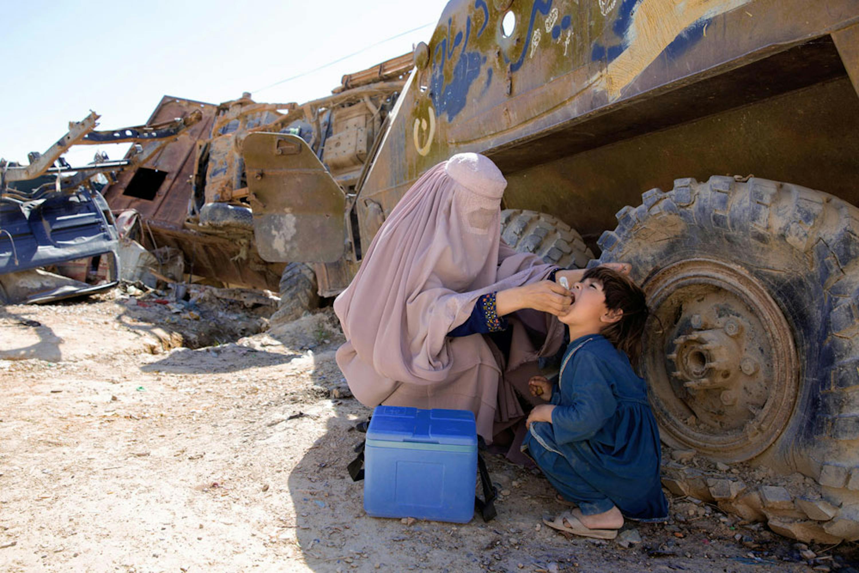 Un bambino riceve una vaccinazione antipolio all'ombra di un carrarmato, in Afghanistan - ©UNICEF/UN0202762/Hibbert