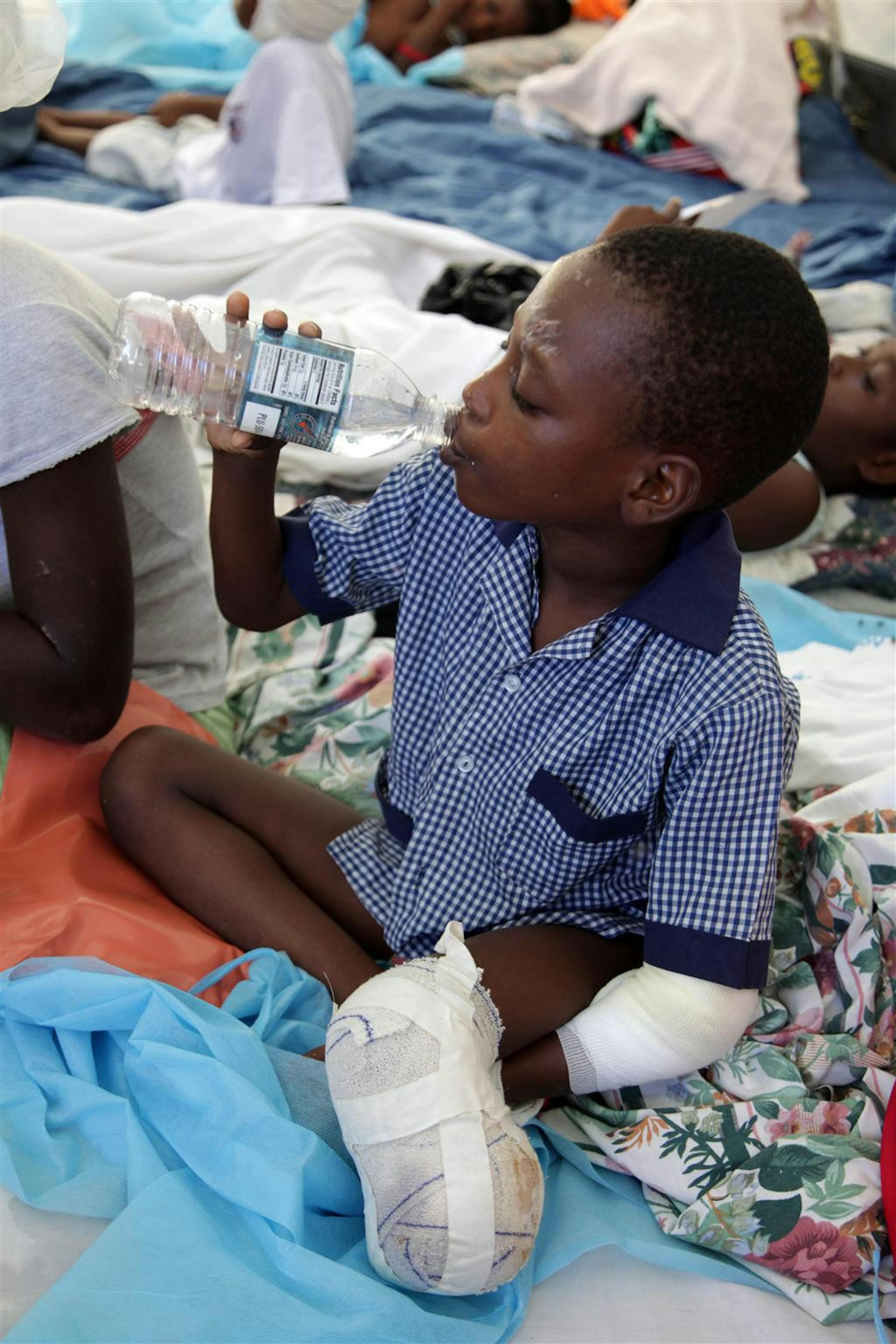 Un bambino che ha subito un'amputazione alla gamba sinistra beve in una tenda dove è stato allestito il reparto pediatrico dell'Ospedale Generale di Port-au-Prince. L'UNICEF rifornisce acqua in bottiglia a quasi tutti gli ospedali della capitale haitiana