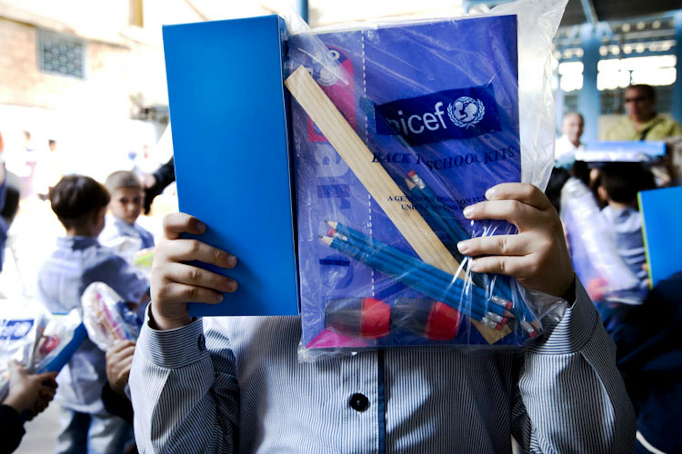 Un bambino del Campo profughi palestinesi di Burj El Barajneh si copre il volto mostrando il kit di materiale scolastico fornitogli dall'UNICEF. ©Ada Lombardi/UNICEF Italia/2010