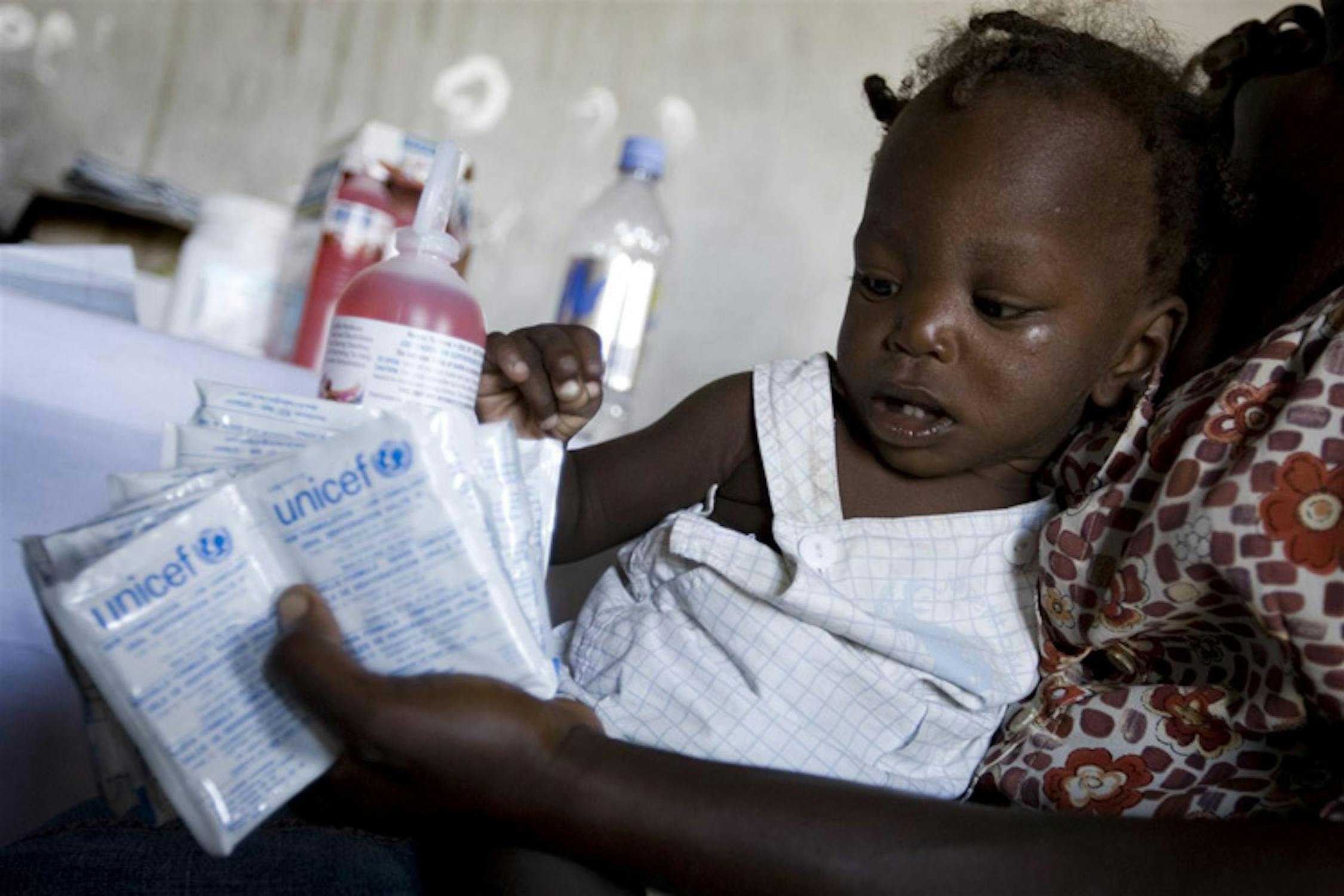 Una madre col suo bambino nell'accettazione dell'ospedale di Grand Dessalines, Haiti: nella sua mano, alcune bustine di sali reidratanti per contrastare la diarrea acutissima provocata dal colera