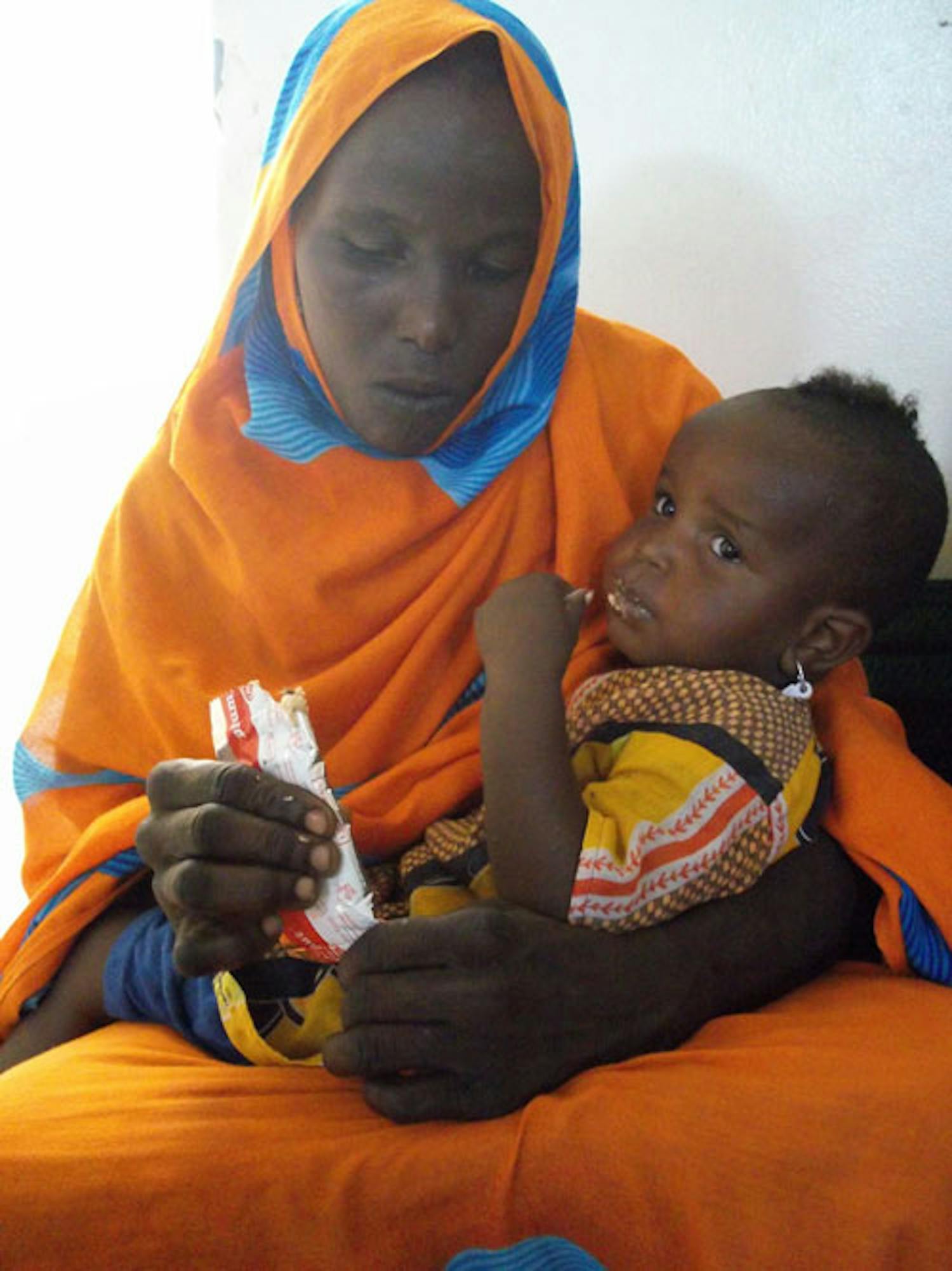 Questo bambino, in braccio alla mamma, mangia il Plumpynut, alimento terapeutico pronto per l'uso. ©Saira Cutrone