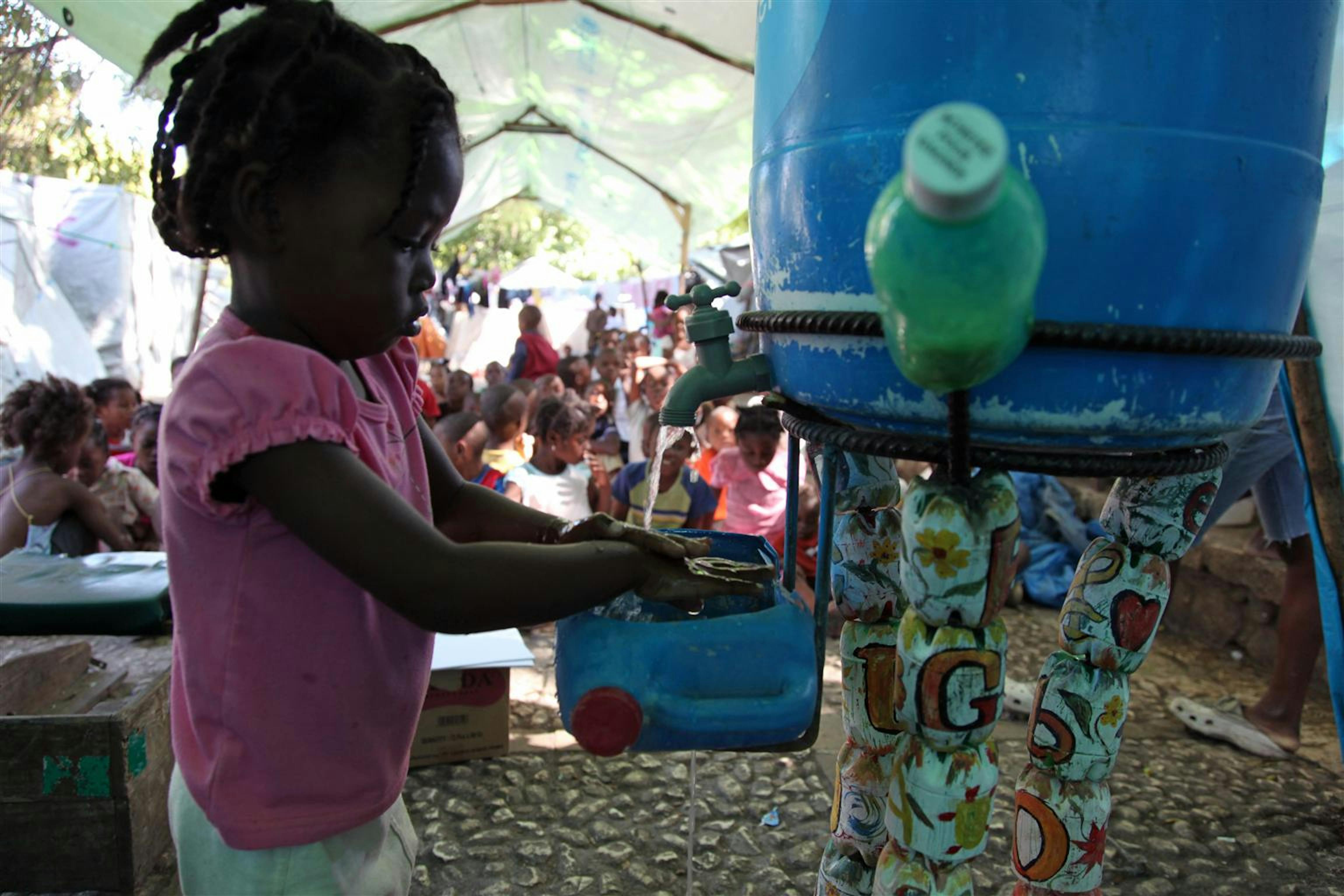 Una bambina prende l'acqua da una cisterna installata dall'UNICEF nel campo per sfollati di Pétionville, un quartiere della capitale di Haiti - ©UNICEF/NYHQ2010-2665/R.LeMoyne