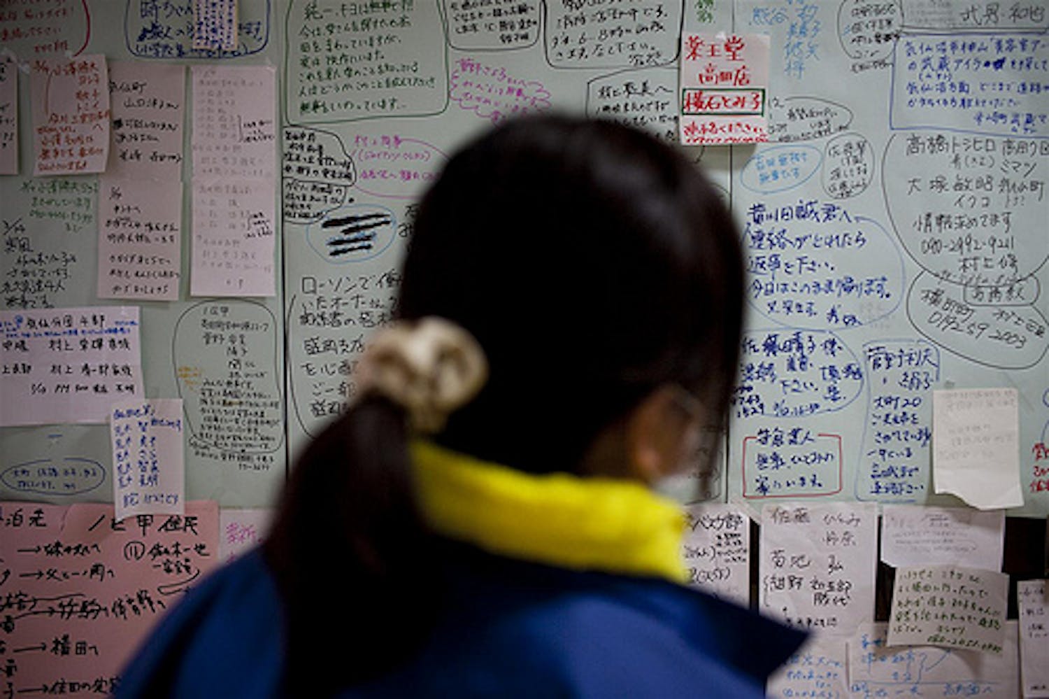 Una donna cerca nominativi di persone care su una bacheca coperta di migliaia di nomi di persone disperse a seguito dello tsunami nella cittadina di Rikuzen-Takaata, nella prefettura di Iwate - ©UNICEF/NYHQ2011-0429/Adam Dean