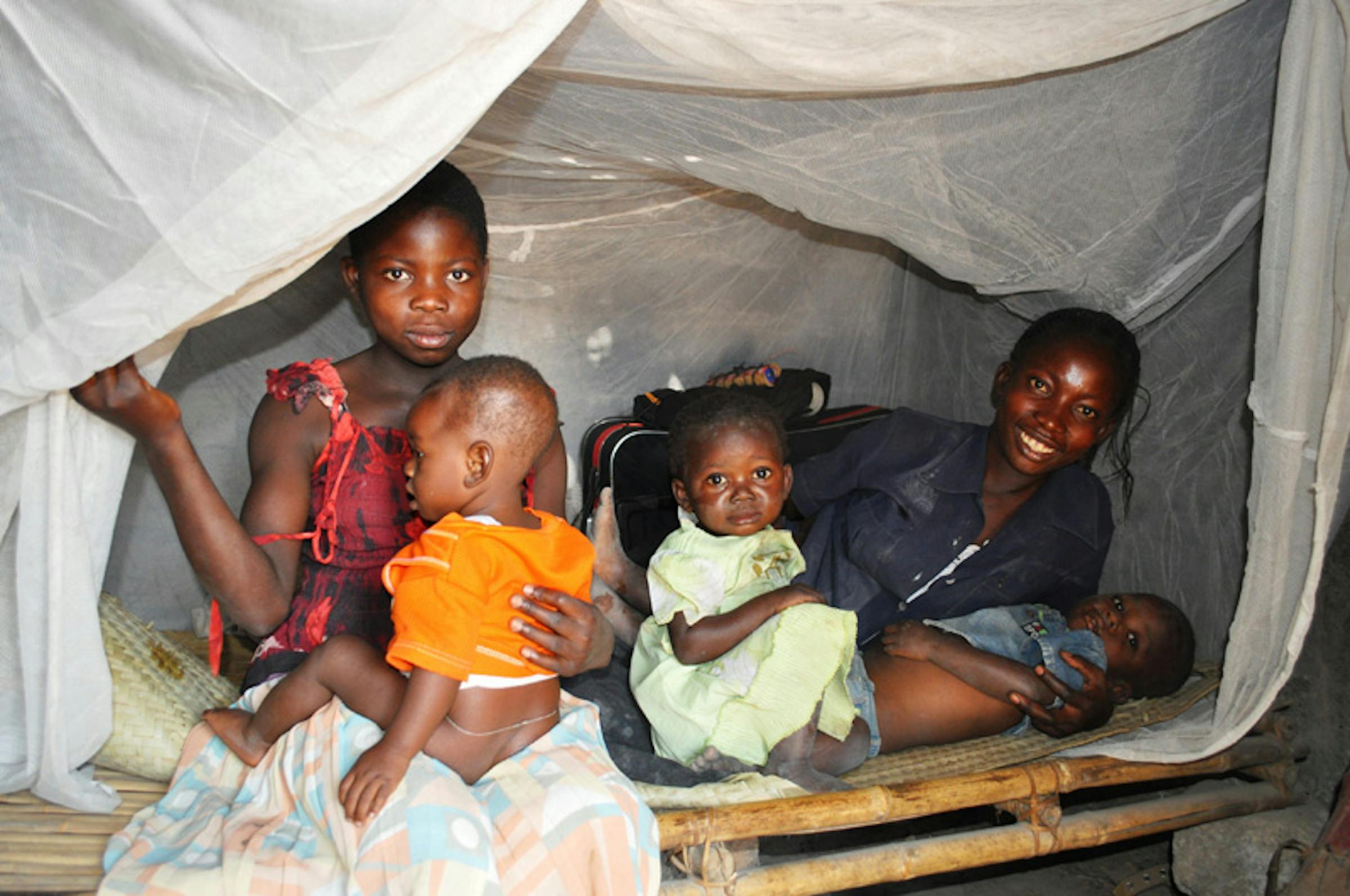 Henriette con i suoi tre figli sotto la zanzariera ricevuta nella campagna di distribuzione del 2012 - ©UNICEF R.D.Congo/2012/Martino