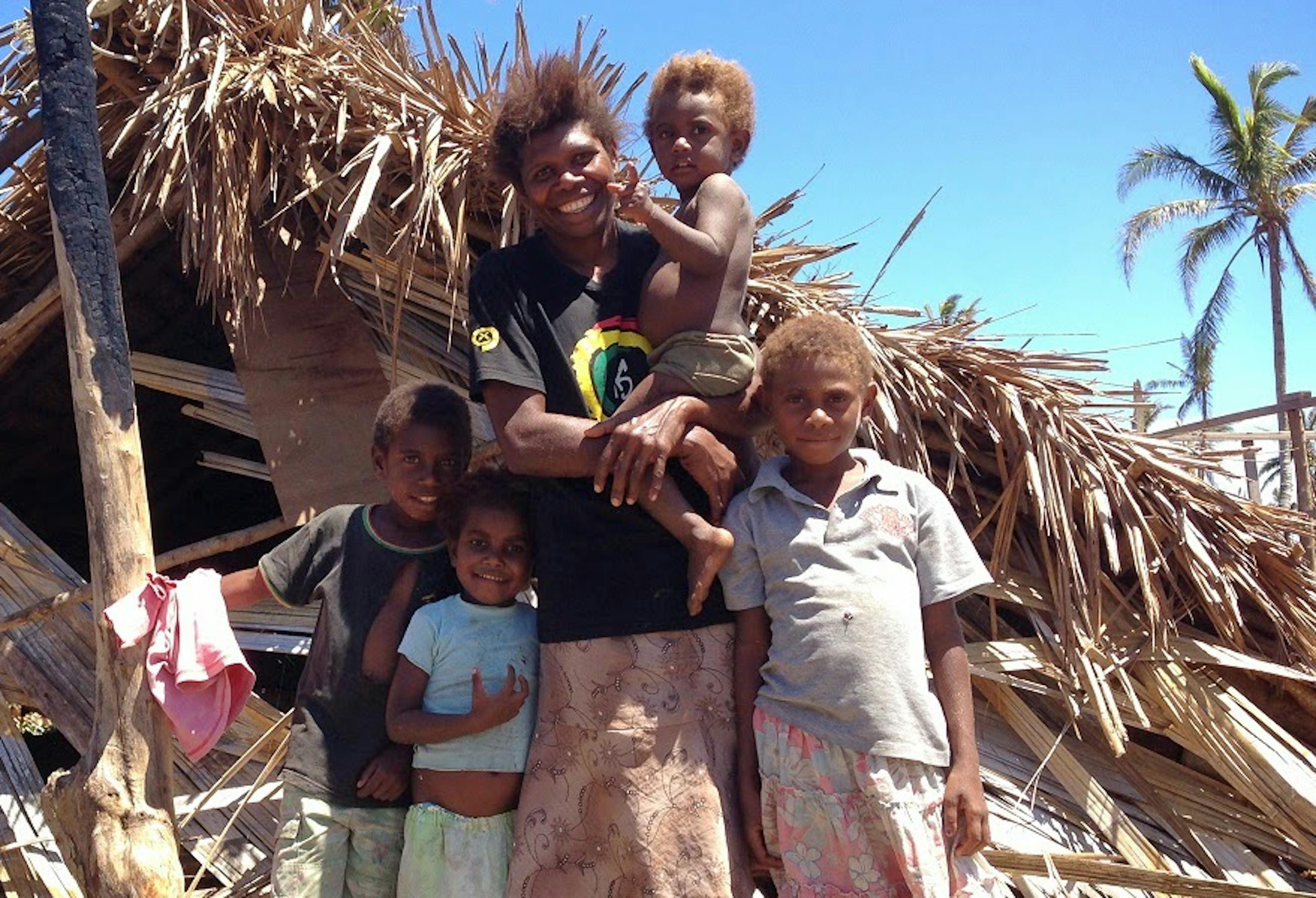 Una famiglia sull'isola Tannu sorride, nonostante la distruzione della sua abitazione - ©UNICEF Pacific/2015/Crumb