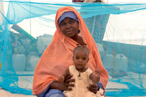 Saratu e il suo bambino, sfuggiti alle incursioni di Boko Haram, hanno una zanzariera per proteggersi dalla malaria nella loro tenda, nel campo per sfollati di Maiduguri, nello stato nigeriano di Borno -  ©UNICEF/NYHQ2015-1981/Andrew Esiebo