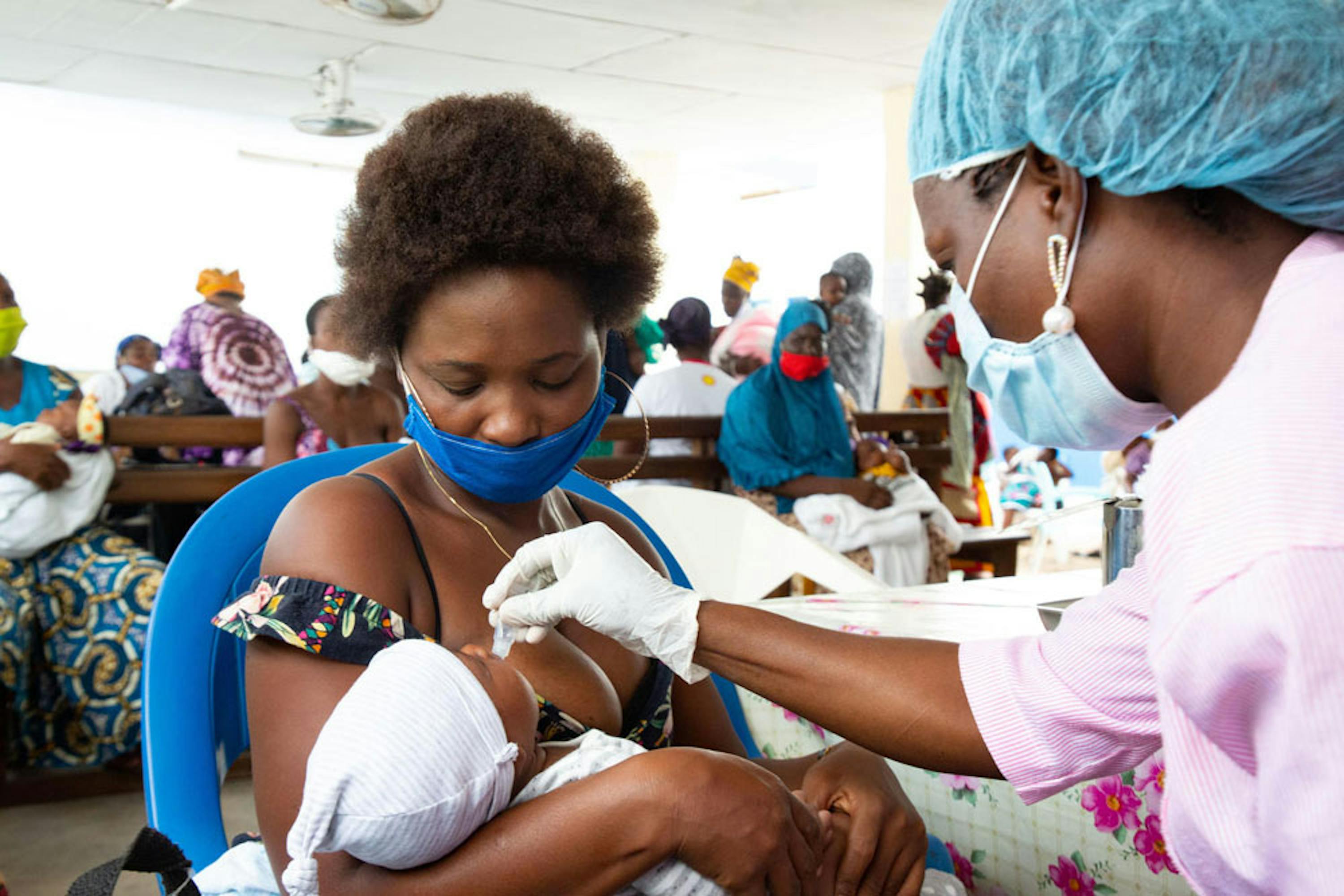 Vaccinazione antipolio di una neonata nell'ospedale di Gonzagueville, sobborgo di Abidjan, capitale della Costa d'Avorio. Mamma e operatrice sanitaria indossano mascherine per proteggersi dal COViD-19 - ©UNICEF/UNI329334/Diarassouba