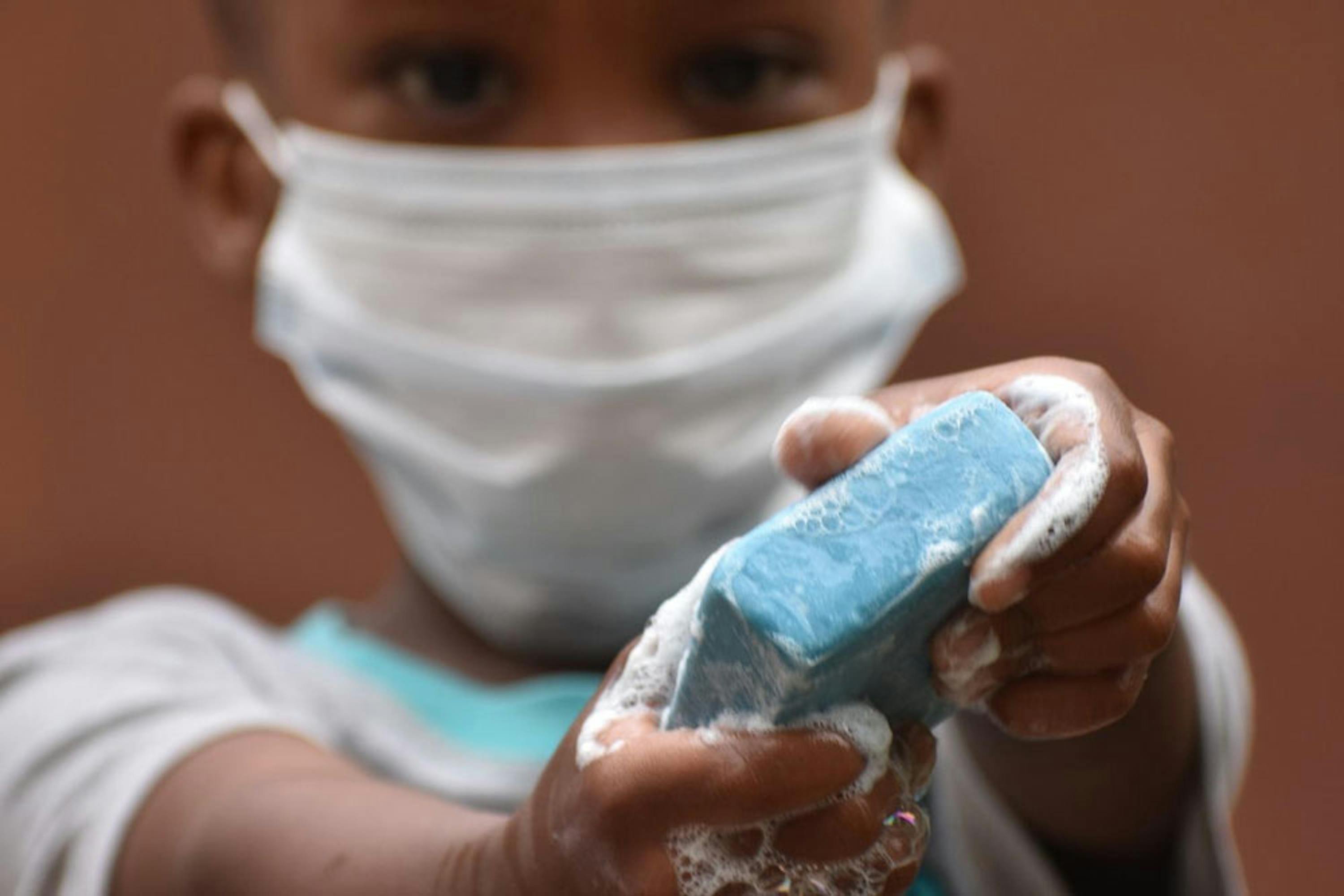 Un bambino si lava le mani con la saponetta blu 