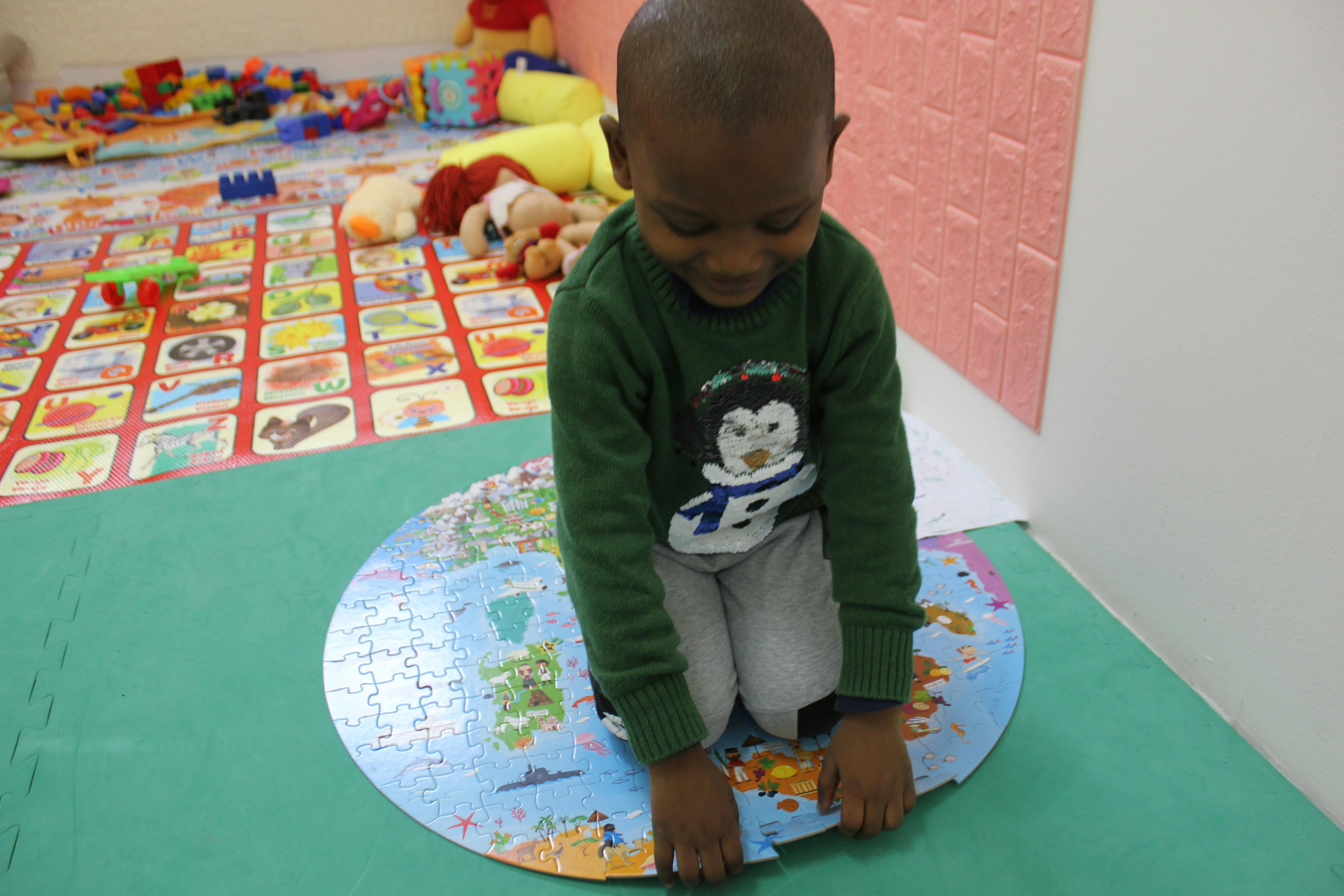 Il piccolo Amari gioca con un puzzle nello spazio bimbi del Women and Girls Safe Space 