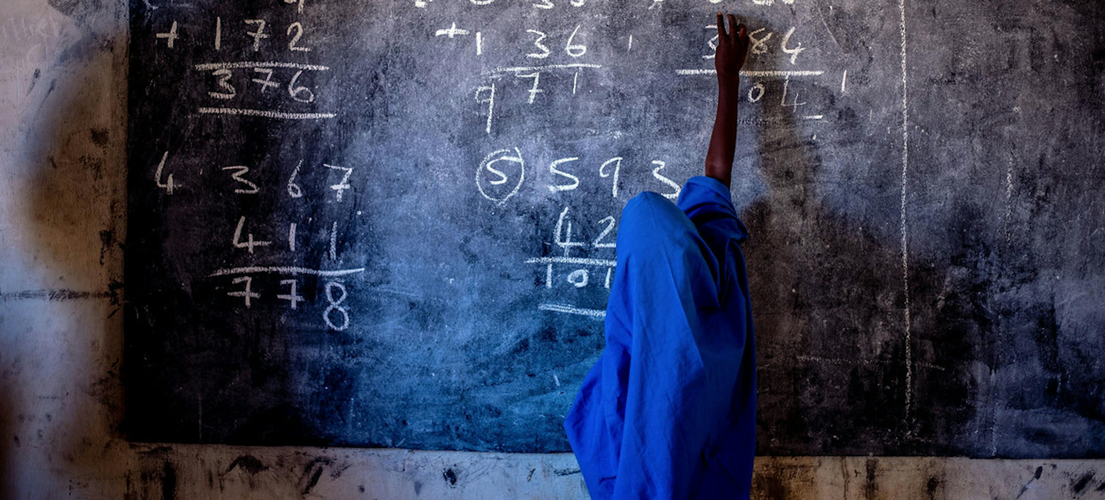 Una ragazza scrive su una lavagna in una scuola elementare in Nigeria