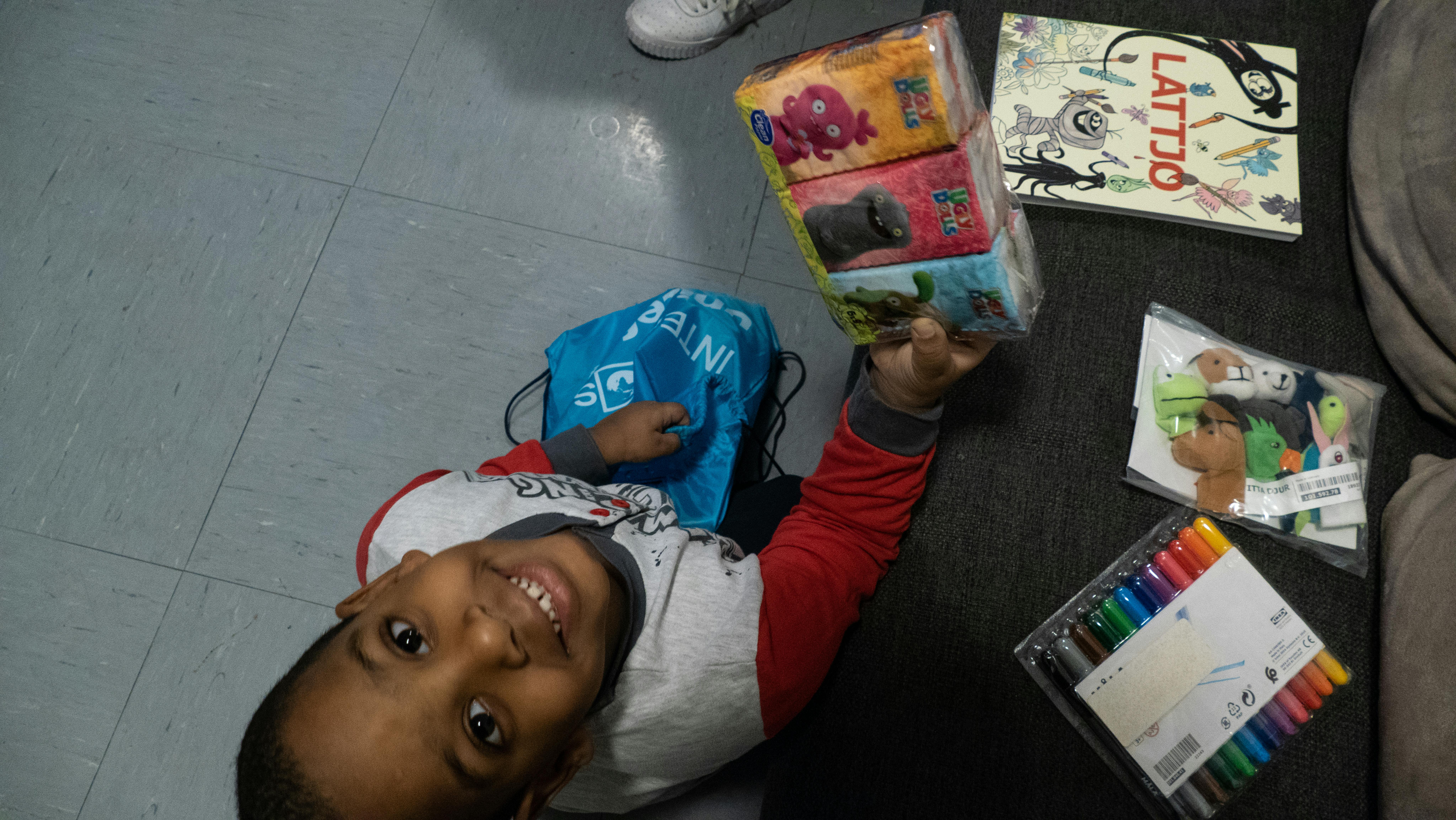 Alexis è felice di aprire la sacca preparata da UNICEF-Intersos