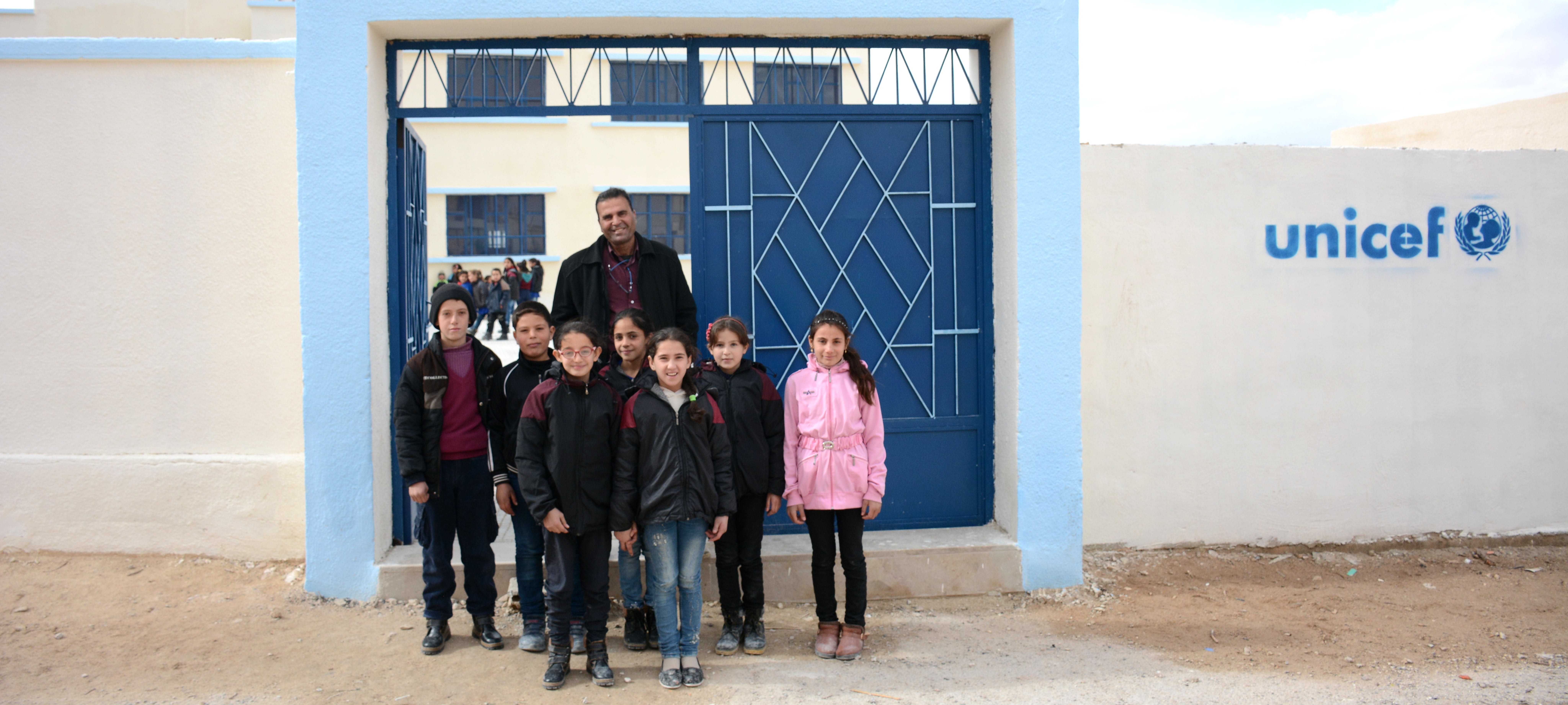 Il Prof Alshawi con alcuni bambini davanti alla scuola ristrutturata grazie ad UNICEF a Maheen, Homs