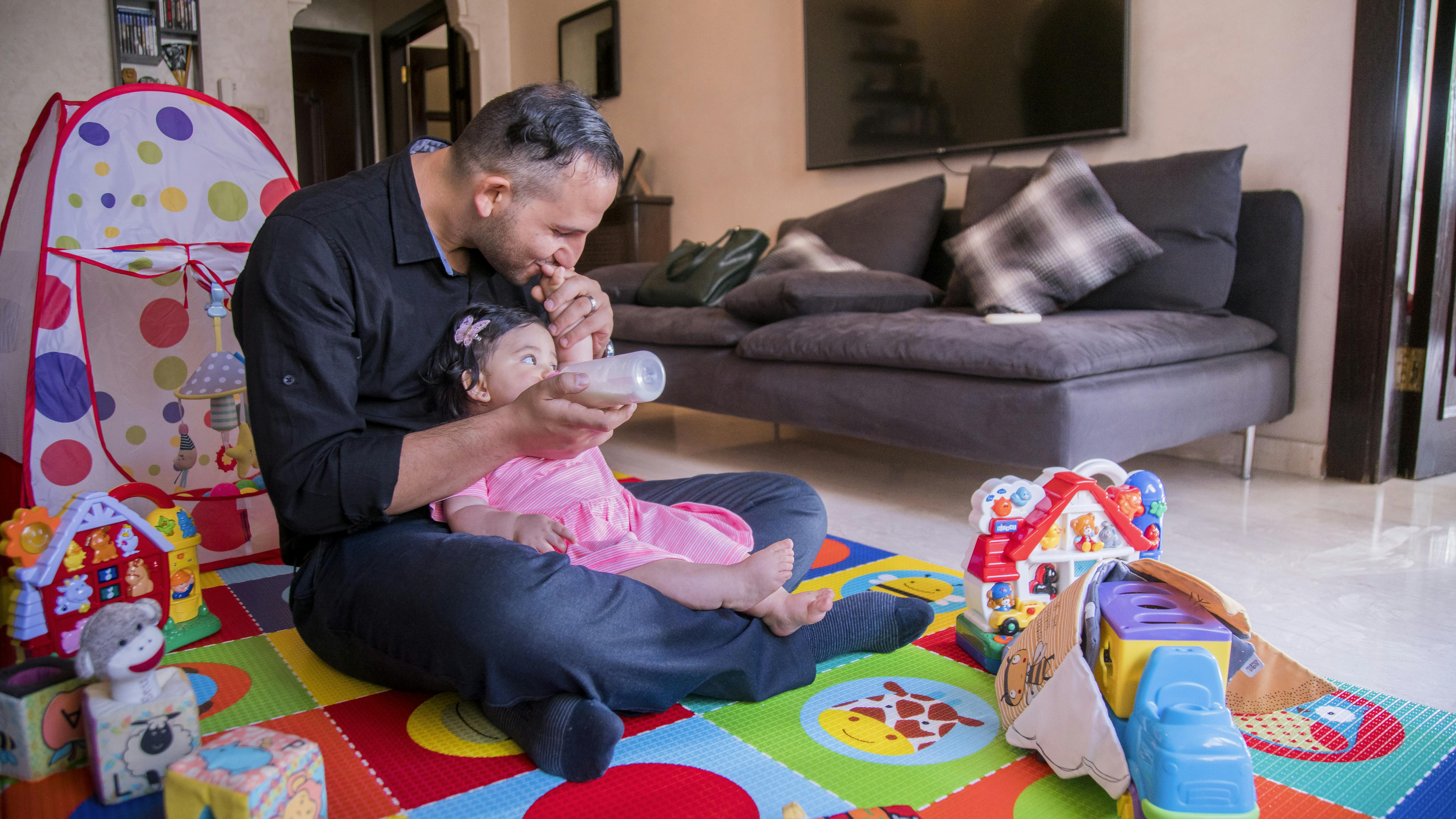 Giordania, Khalid Abu Sahrif allatta con il biberon sua figlia Talya, 9 mesi.