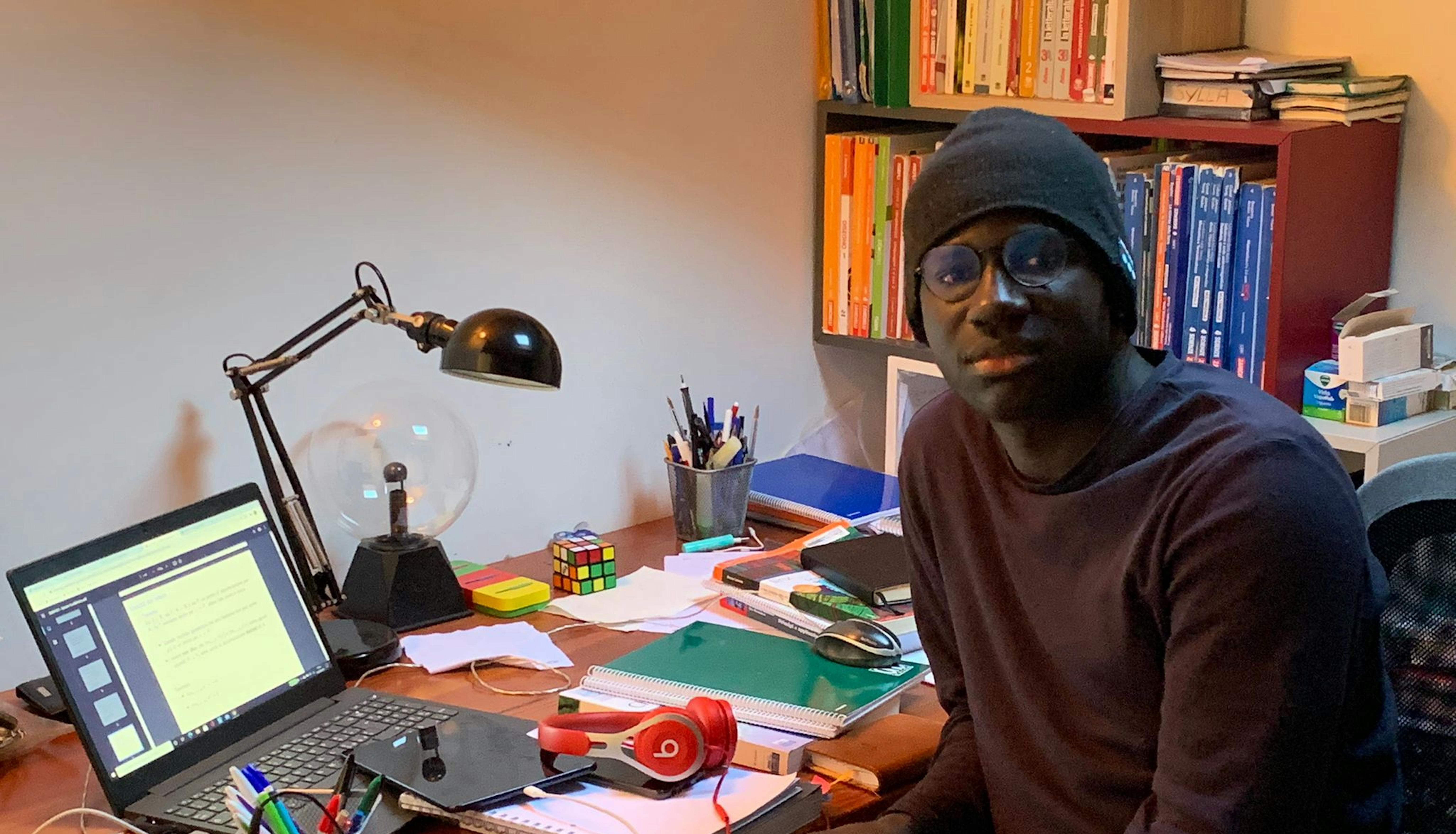 Almamy studia nella sua stanza, nella casa di Milano in cui vive con la sua famiglia affidataria