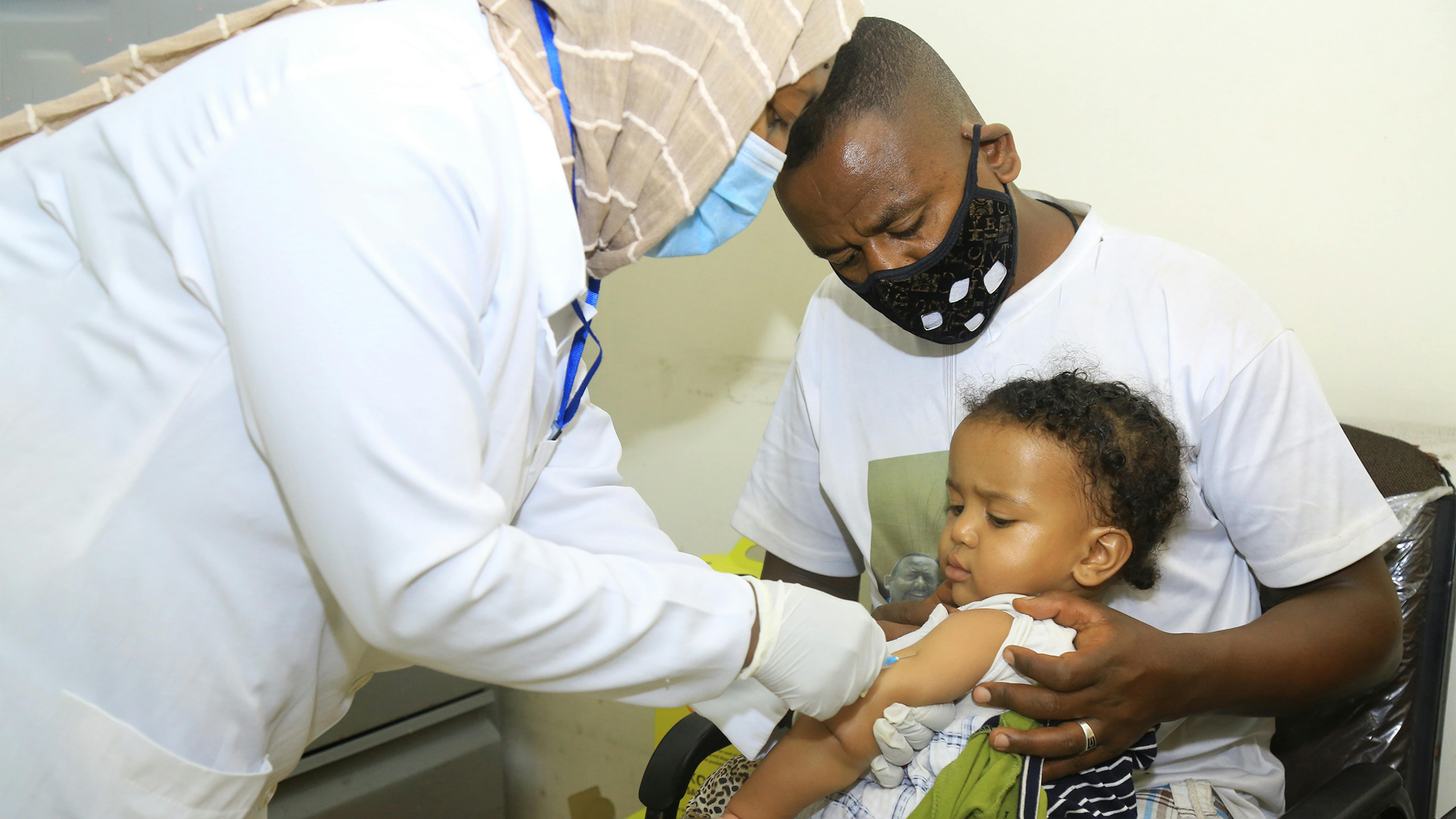 Etiopia, un papà tiene in braccio sua figlia mentre le viene somminstrato il vaccino presso il centro sanitario Woreda 03 di Addis Abeba