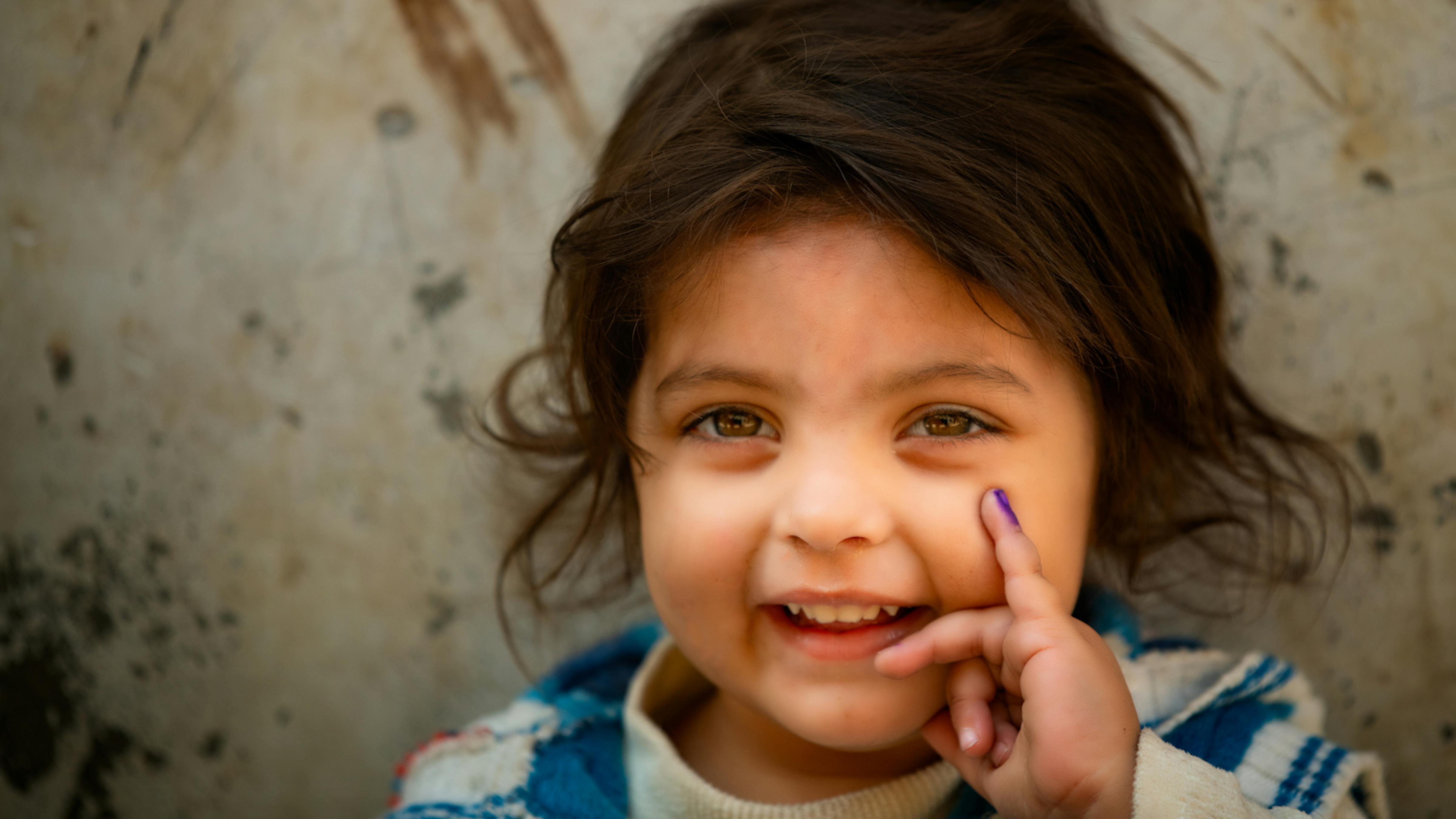 Pakistan, una bambina di tre anni mostra il suo dito segnato dopo aver ricevuto il vaccino antipolio.