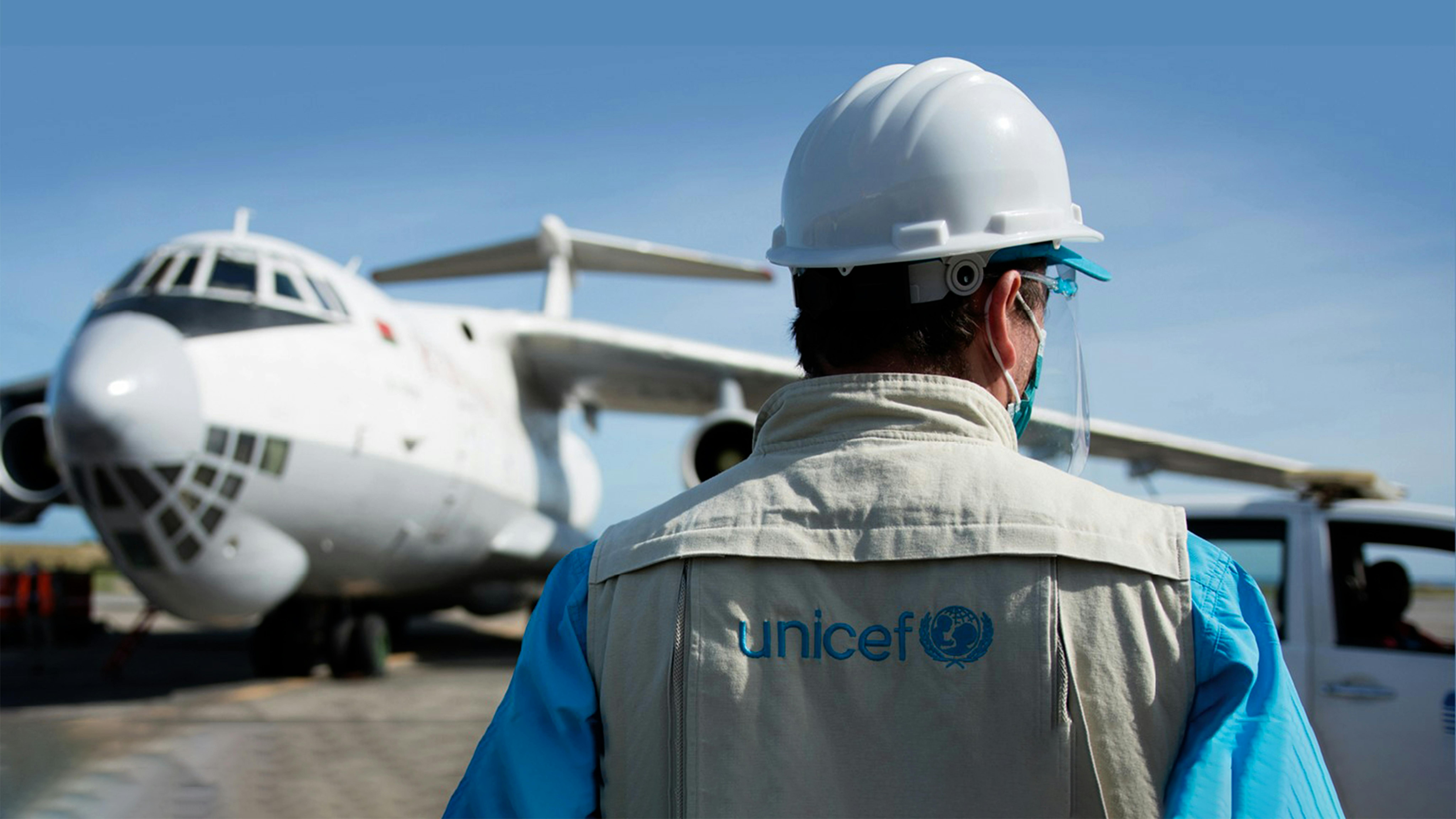 Un operatore UNICEF aspetta che venga scaricato l'aereo con le forniture COVAX