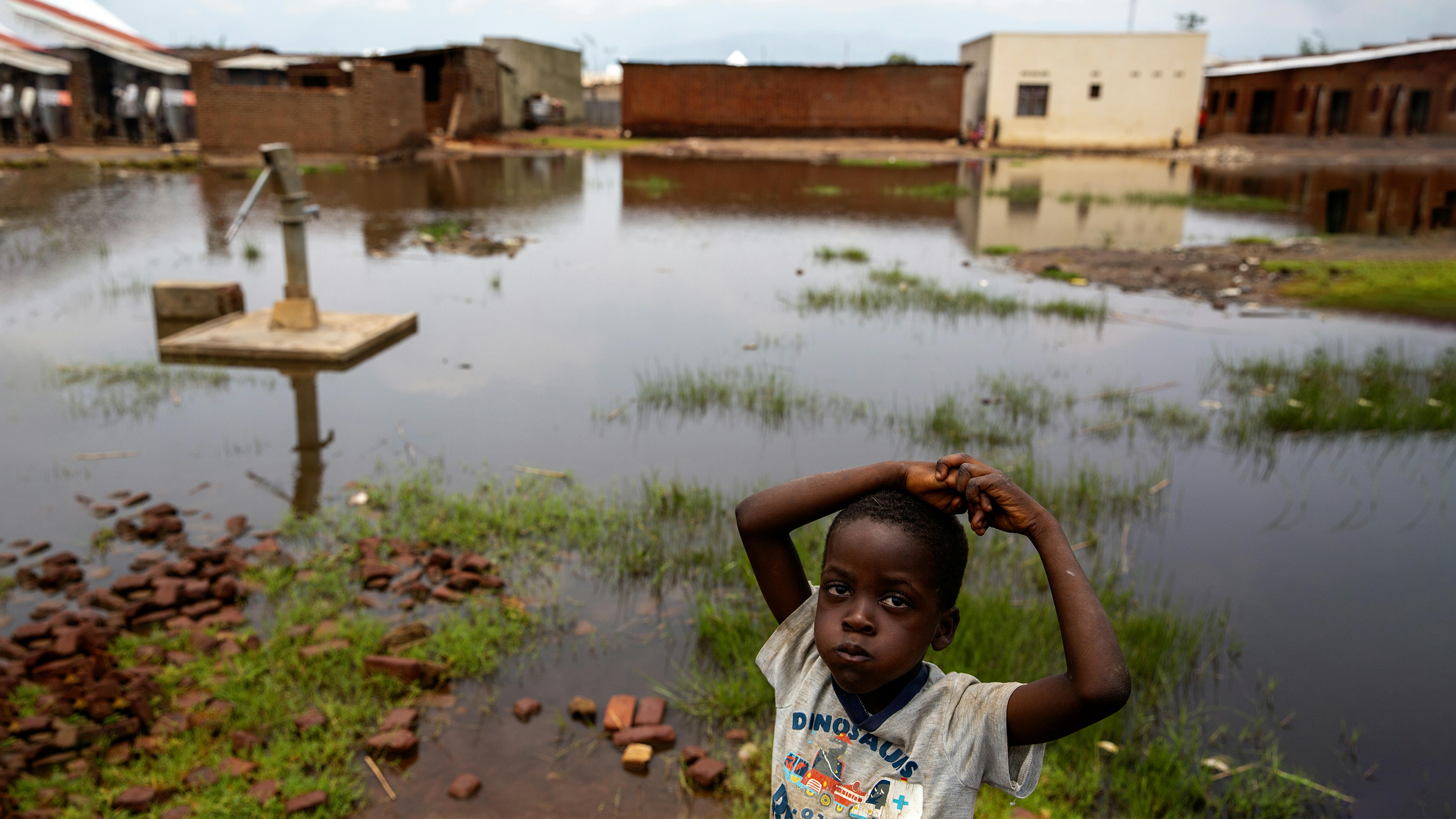Burundi, un bambino in piedi vicino a una pompa dell'acqua circondato dalle acque alluvionali a Gatumba