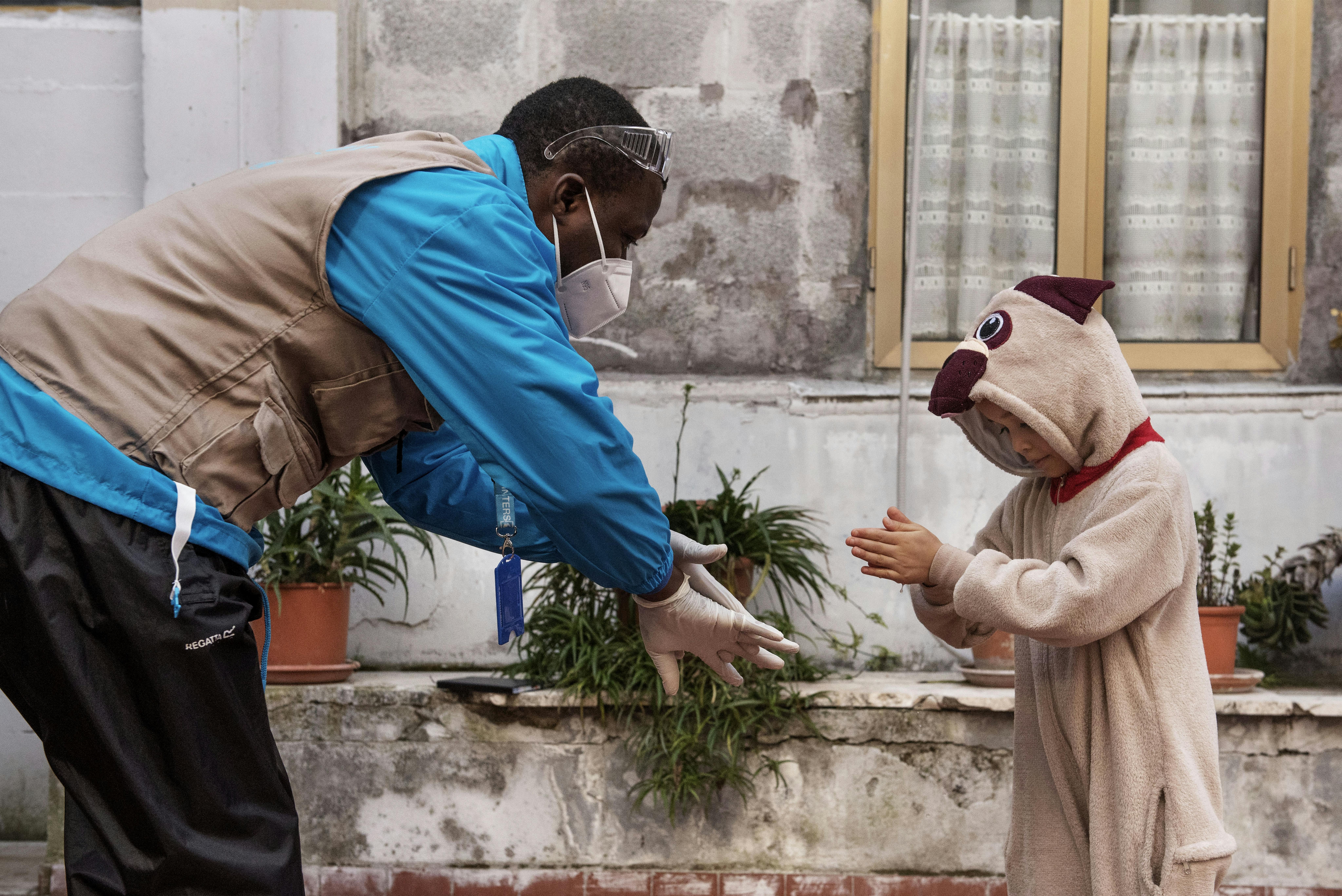 Roma. Un operatore UNICEF-InterSos mostra come  igienizzare le mani a una bambina in un insediamento informale nella capitale
