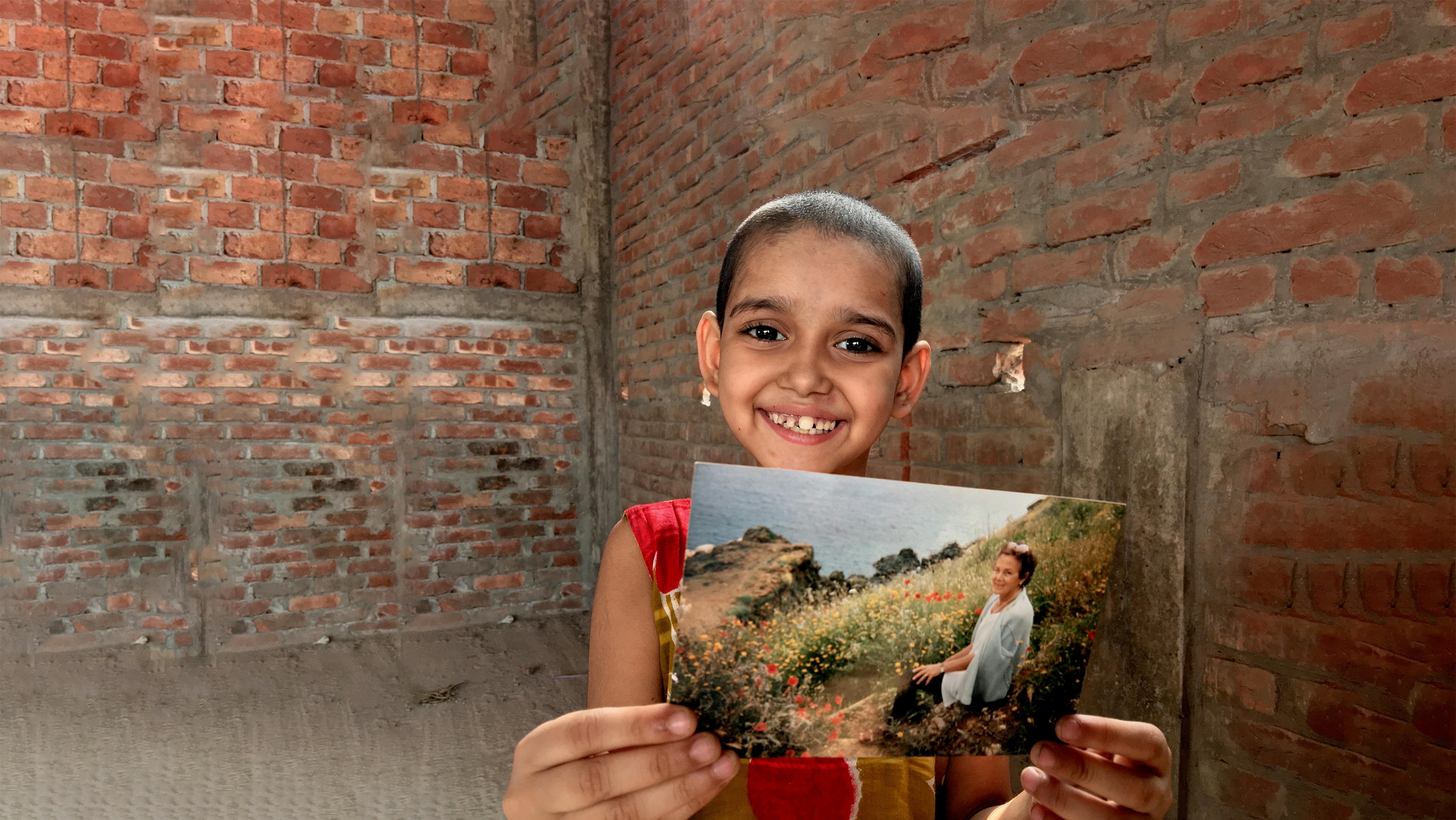Bambina tiene in mano la foto di una donna - donazioni in memoria