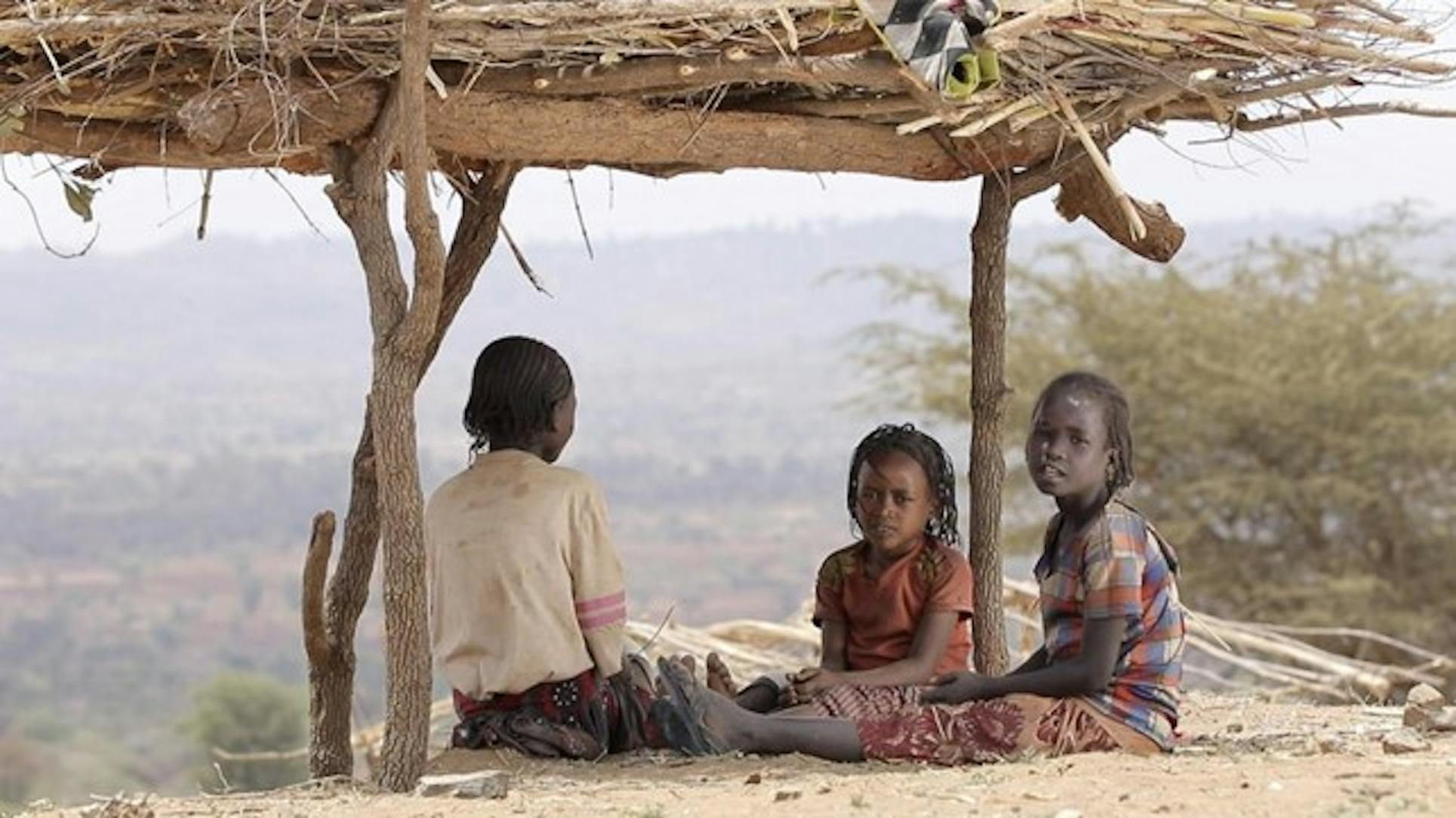 Bambini sfollati si riparano sotto una capanna di legno e paglia, in Etiopia