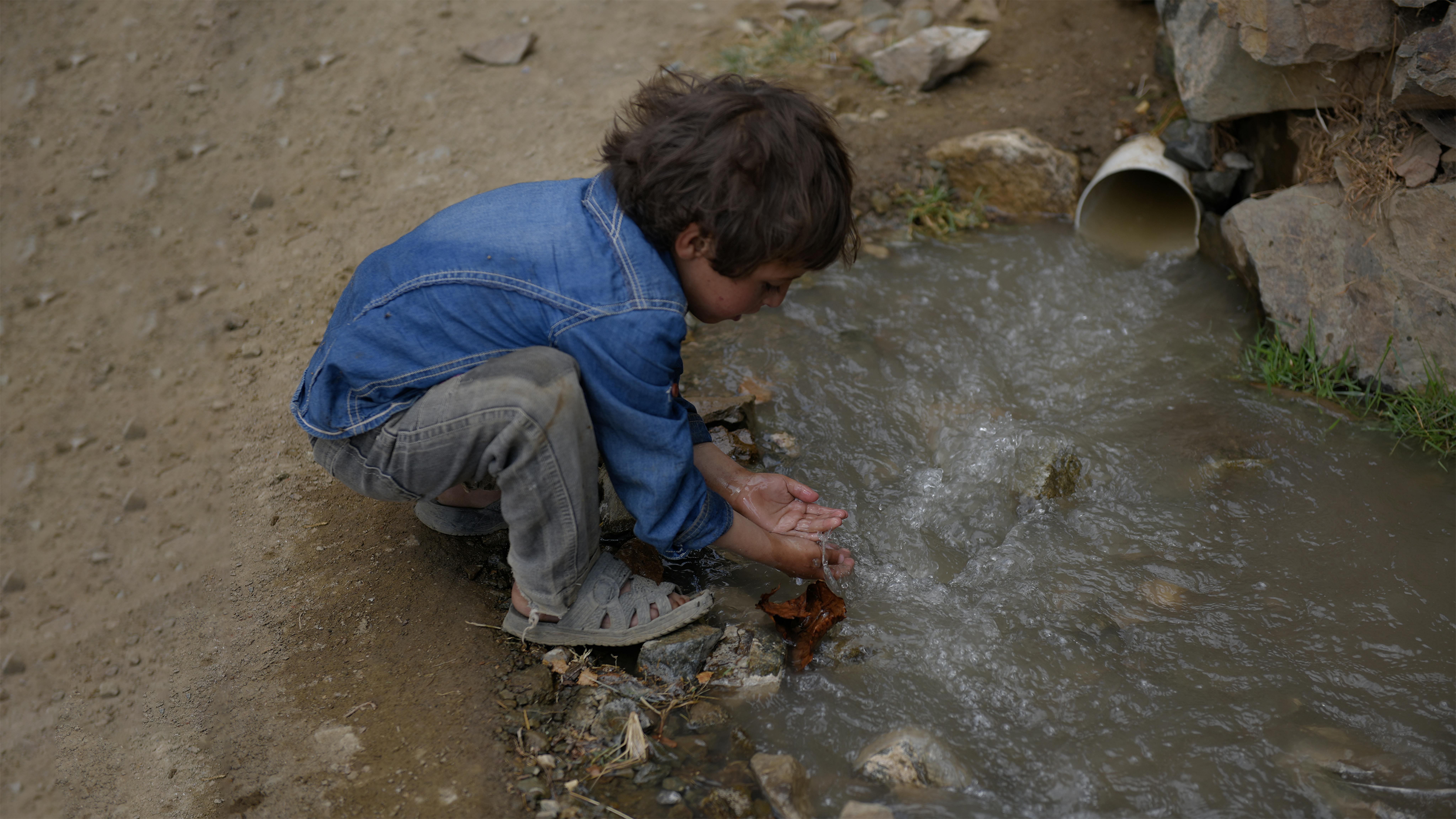 Un bambino si lava le mani con acqua non trattata proveniente da un tubo di fognatura nel governatorato di Amran, Yemen,