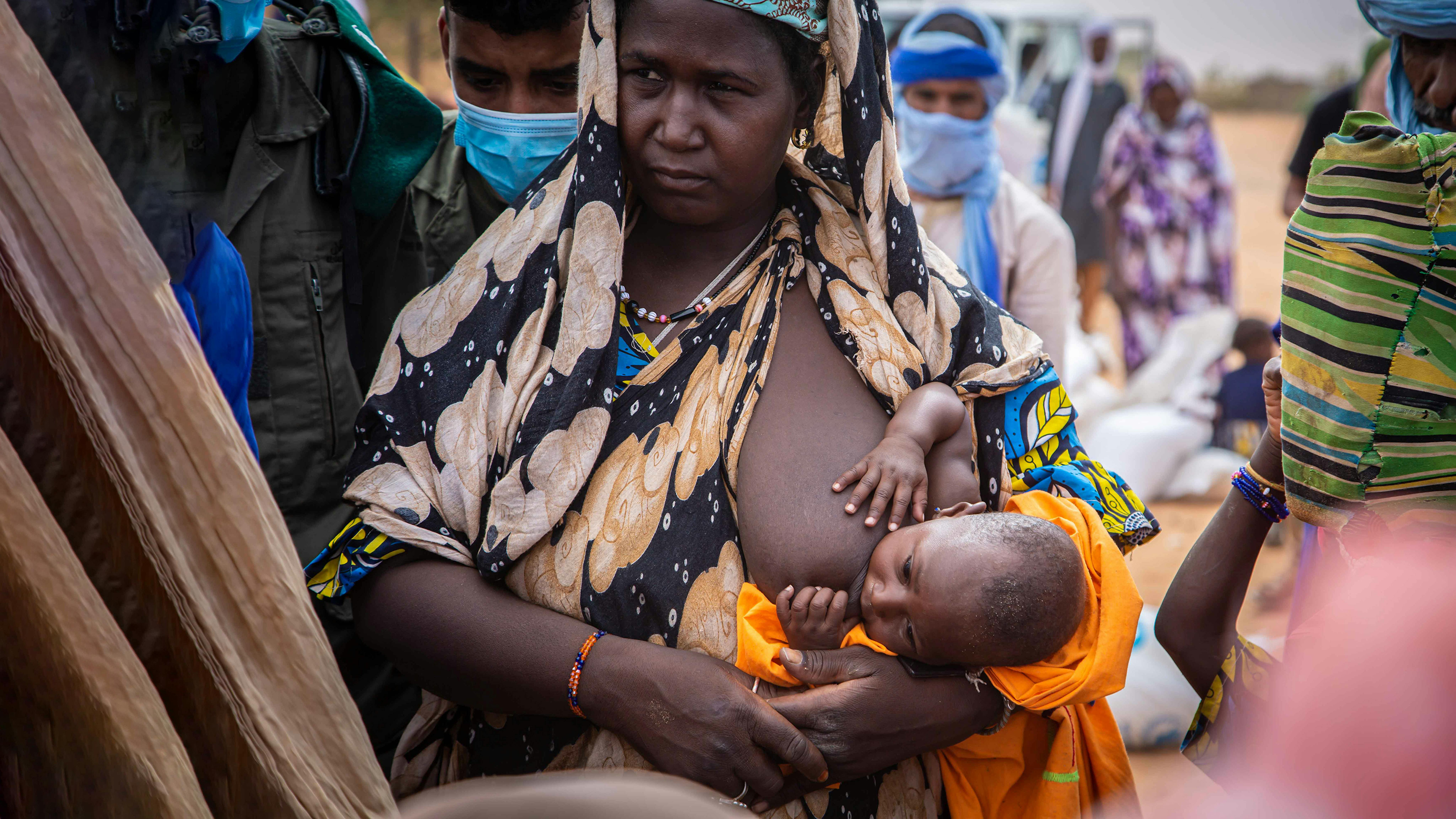 Mauritania - Una rifugiata maliana allatta il suo bambino mentre lascia il centro di distribuzione di cibo nel campo di Mbera.
